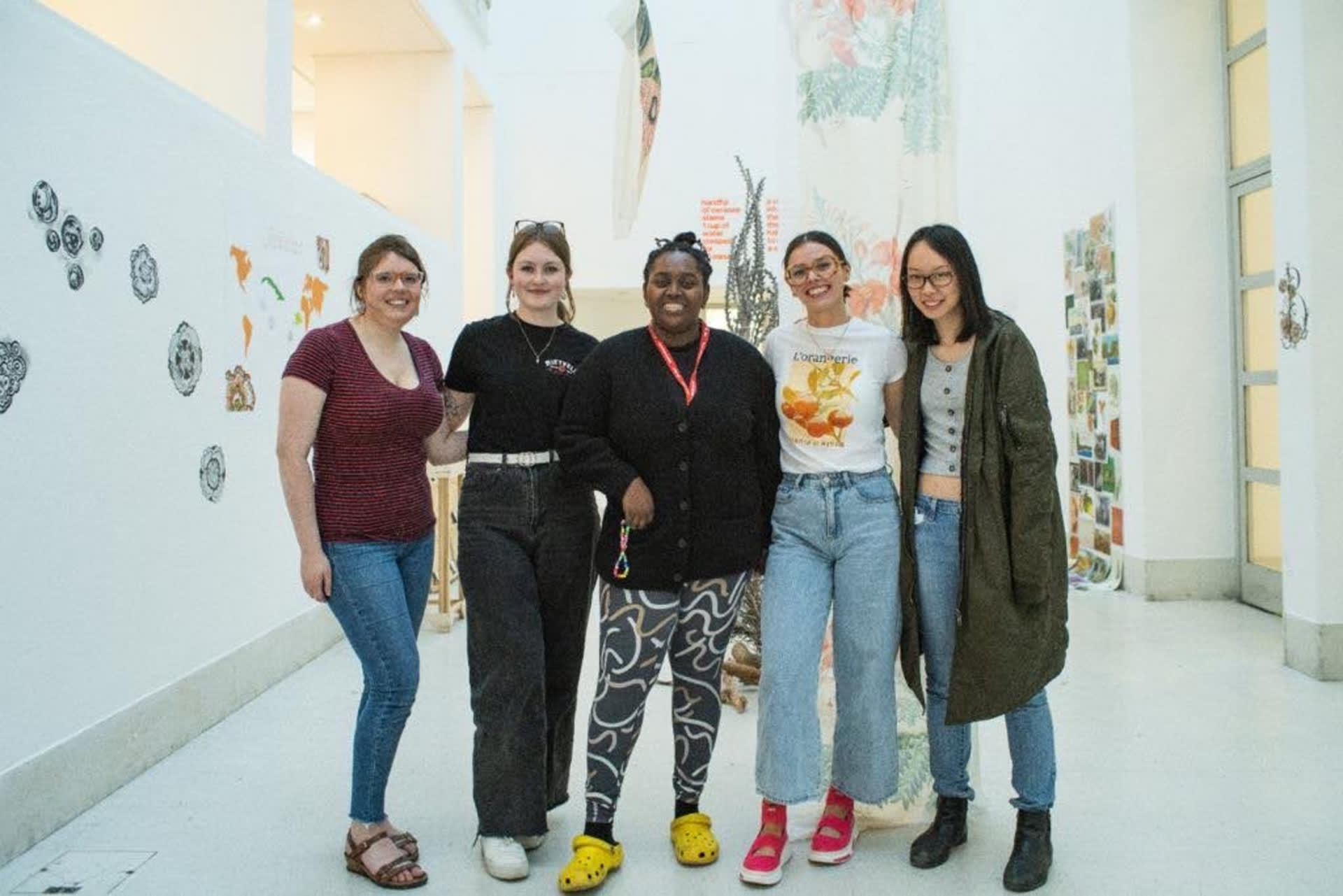 Five women posing for photo in front of final staging of 'Black Botanicals' exhibition 