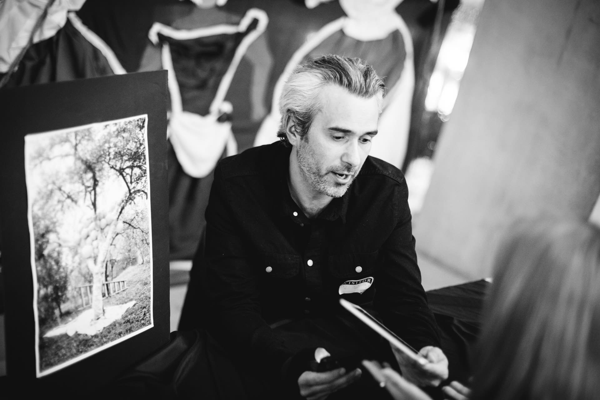 A black and white photograph of Justin performing 'Infinita Ova', an AR haptic poem at Tate Lates at the Tate Modern.