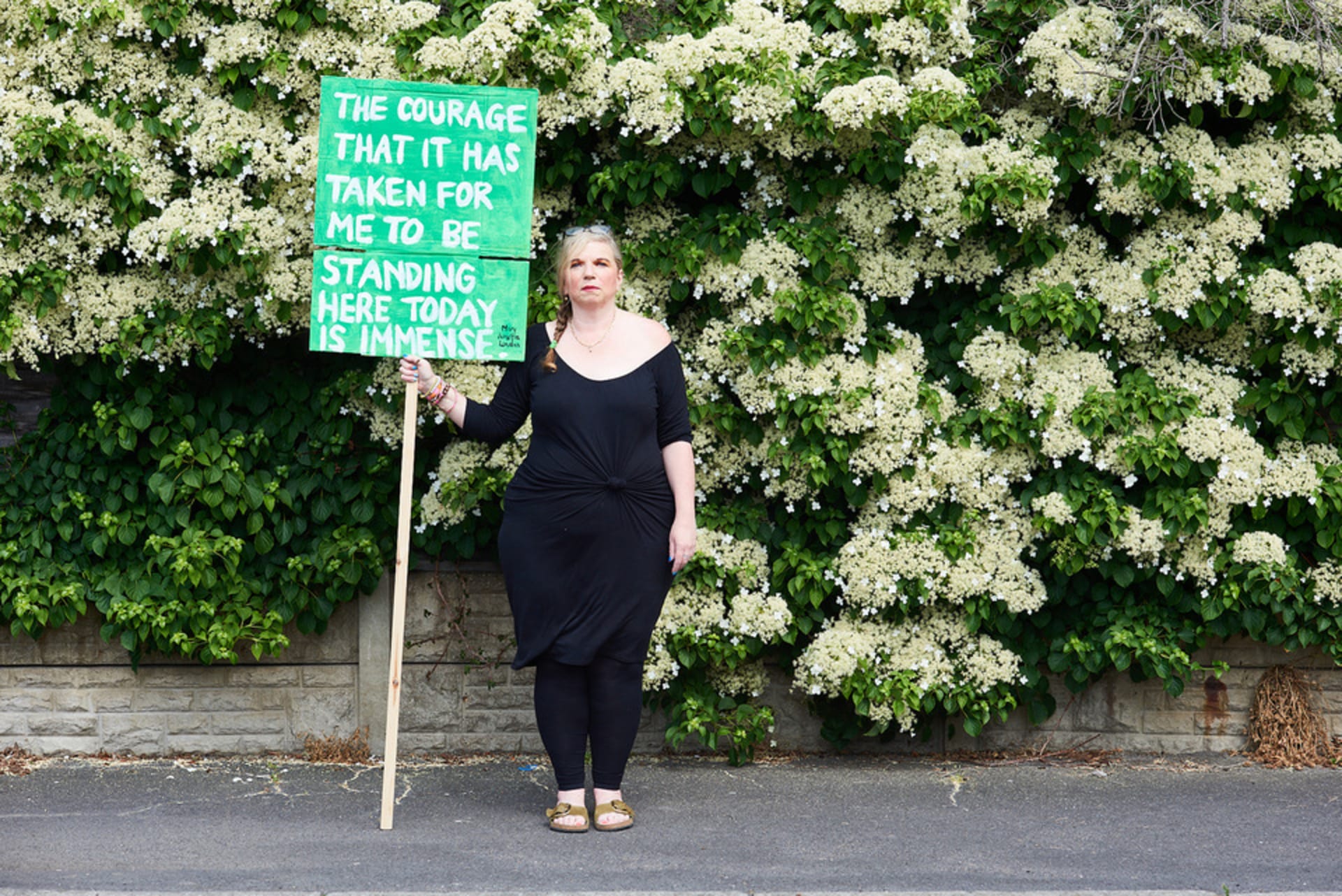 Mary Amelia London holding a sign saying 'The courage that it has taken for me to be standing here today is immense.' 