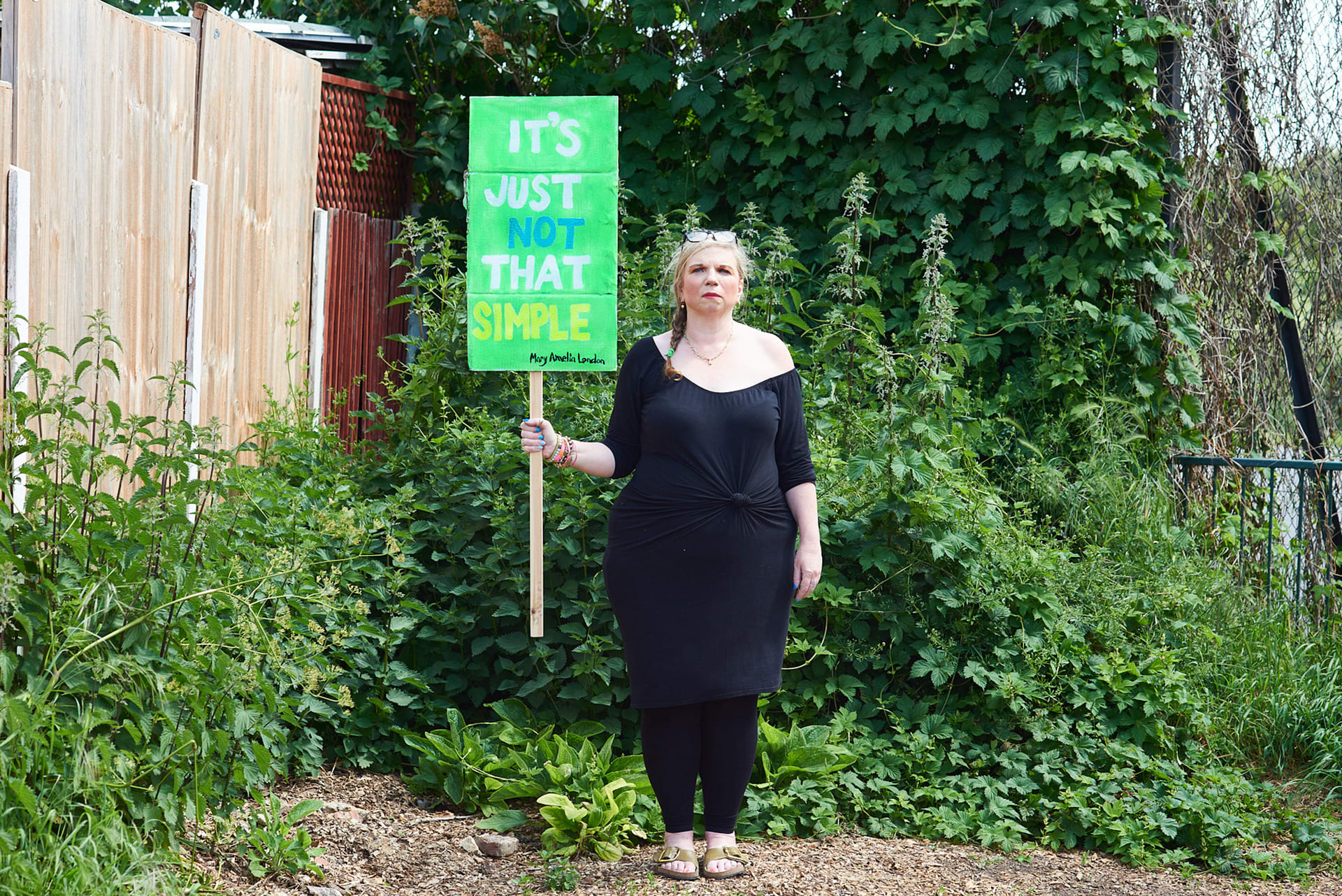 Mary Amelia London stands holding a sign saying: 'It's just not that simple'