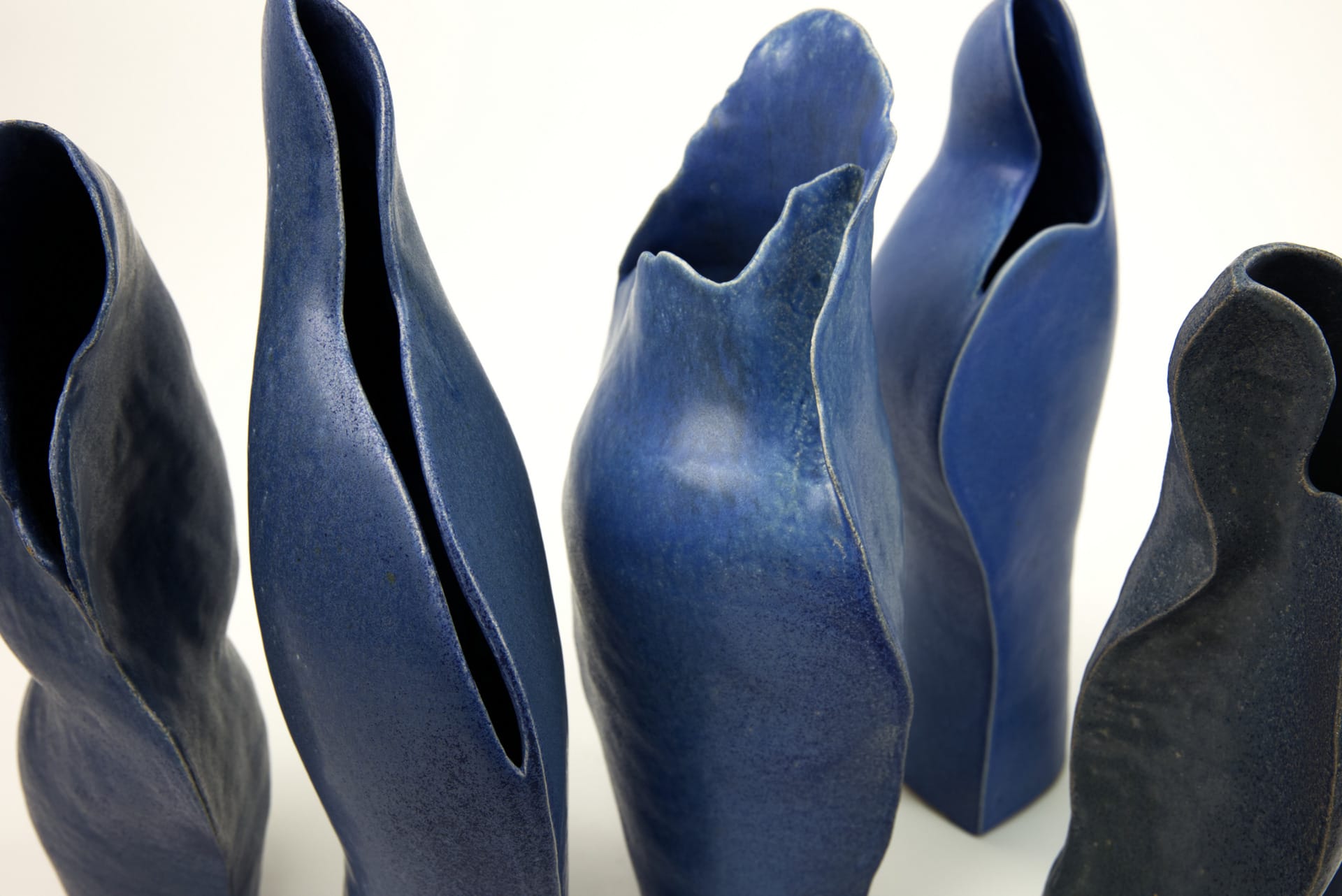 part of 5 curved blue ceramic vessels pictured by top-view.