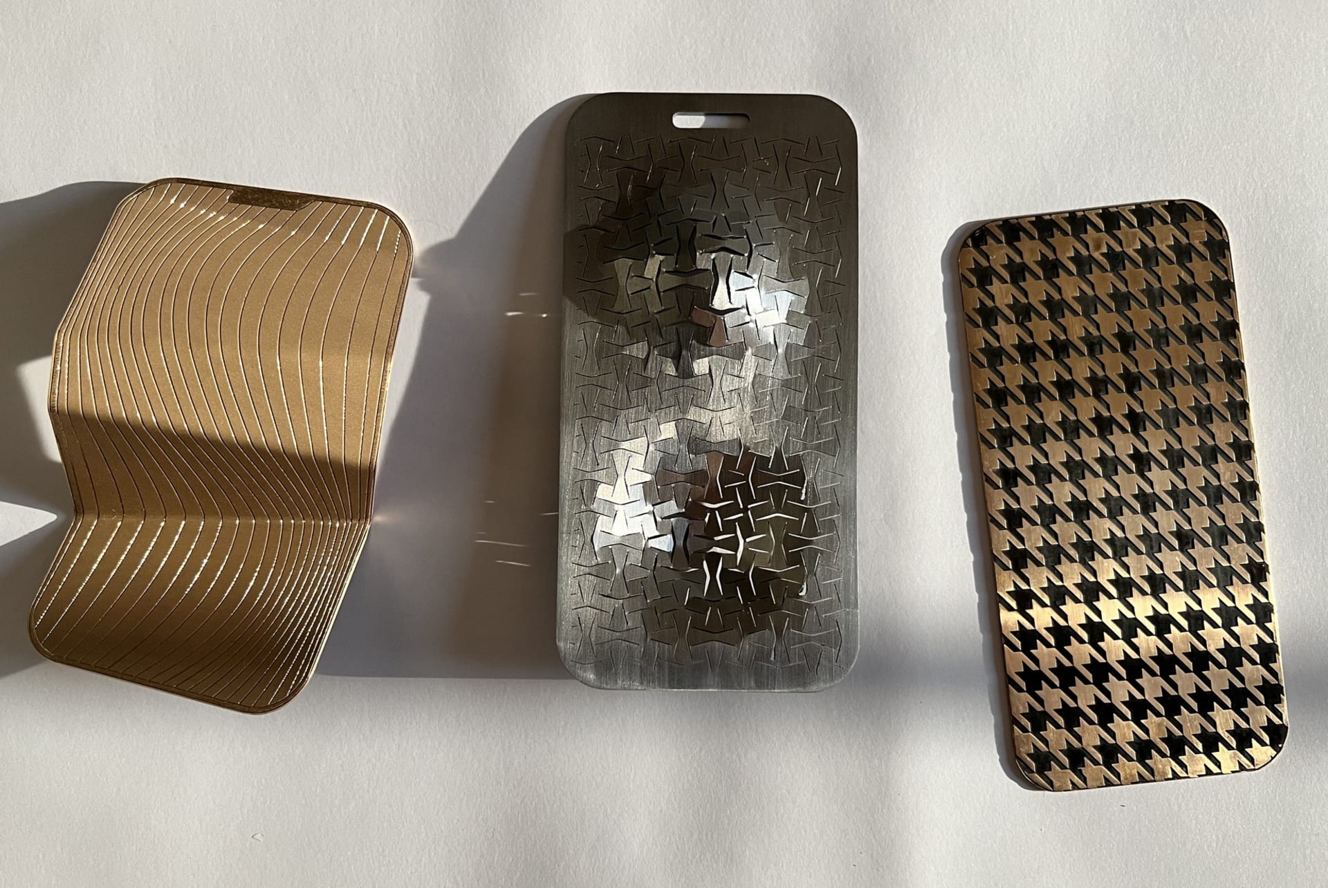 Three smart phones fabricated in metal sheets with various techniques and patinas including folding and laser cutting.