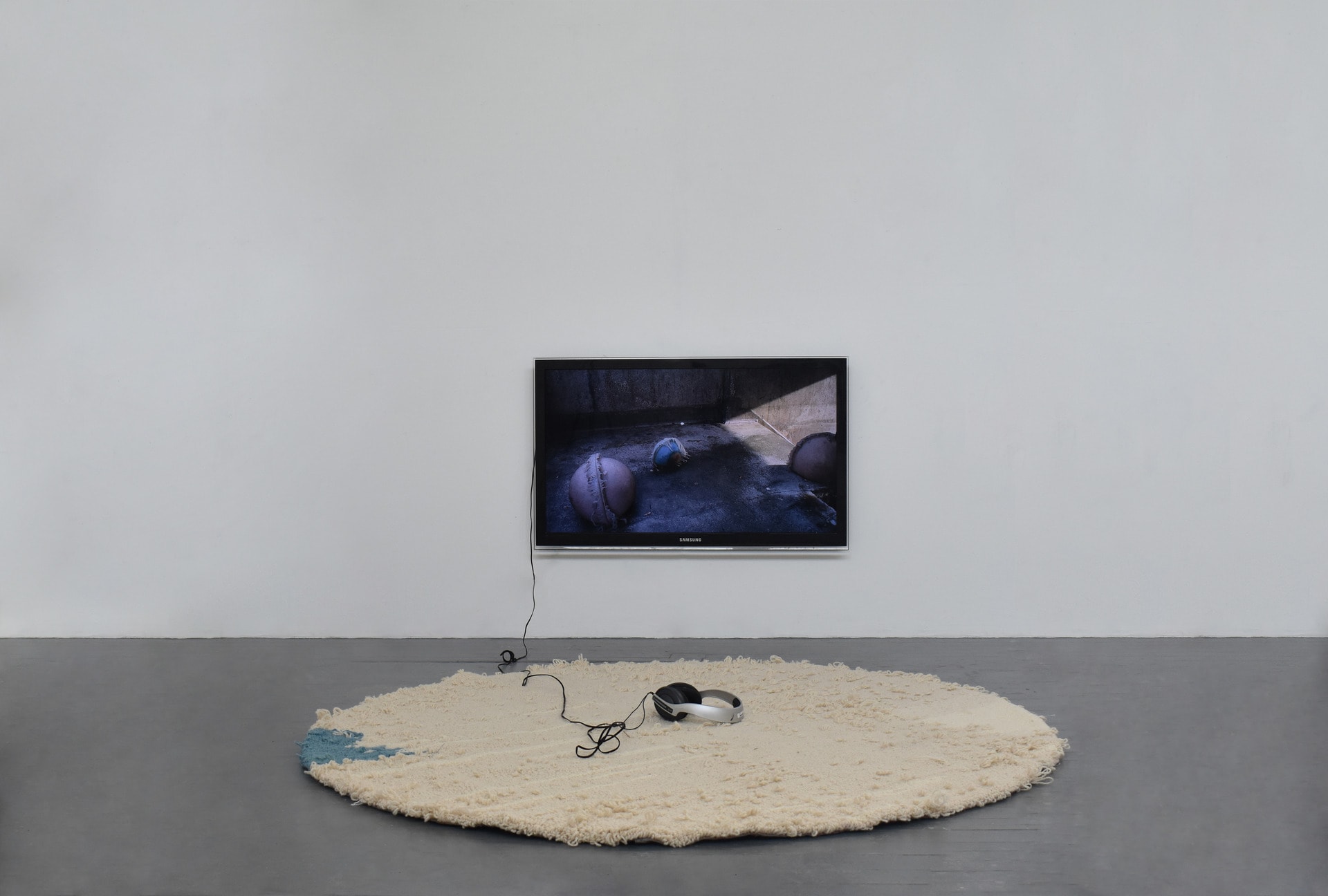 Hand Tufted rug in front of screen displaying cyclical video of silicone orbs rocking.