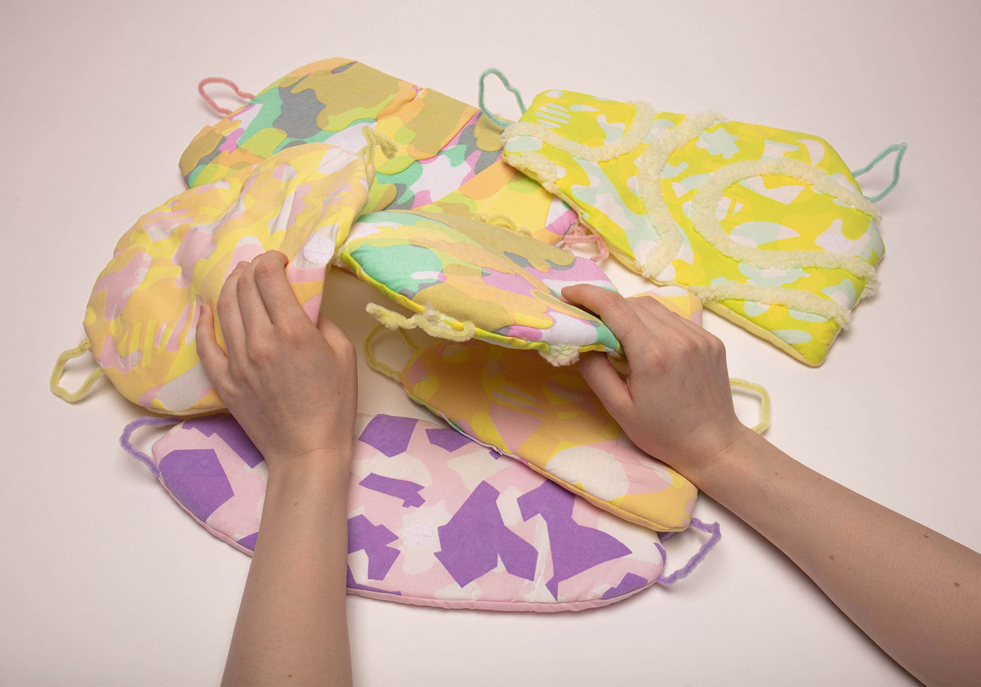 Two hands interacting with multi-colour textile patches. 