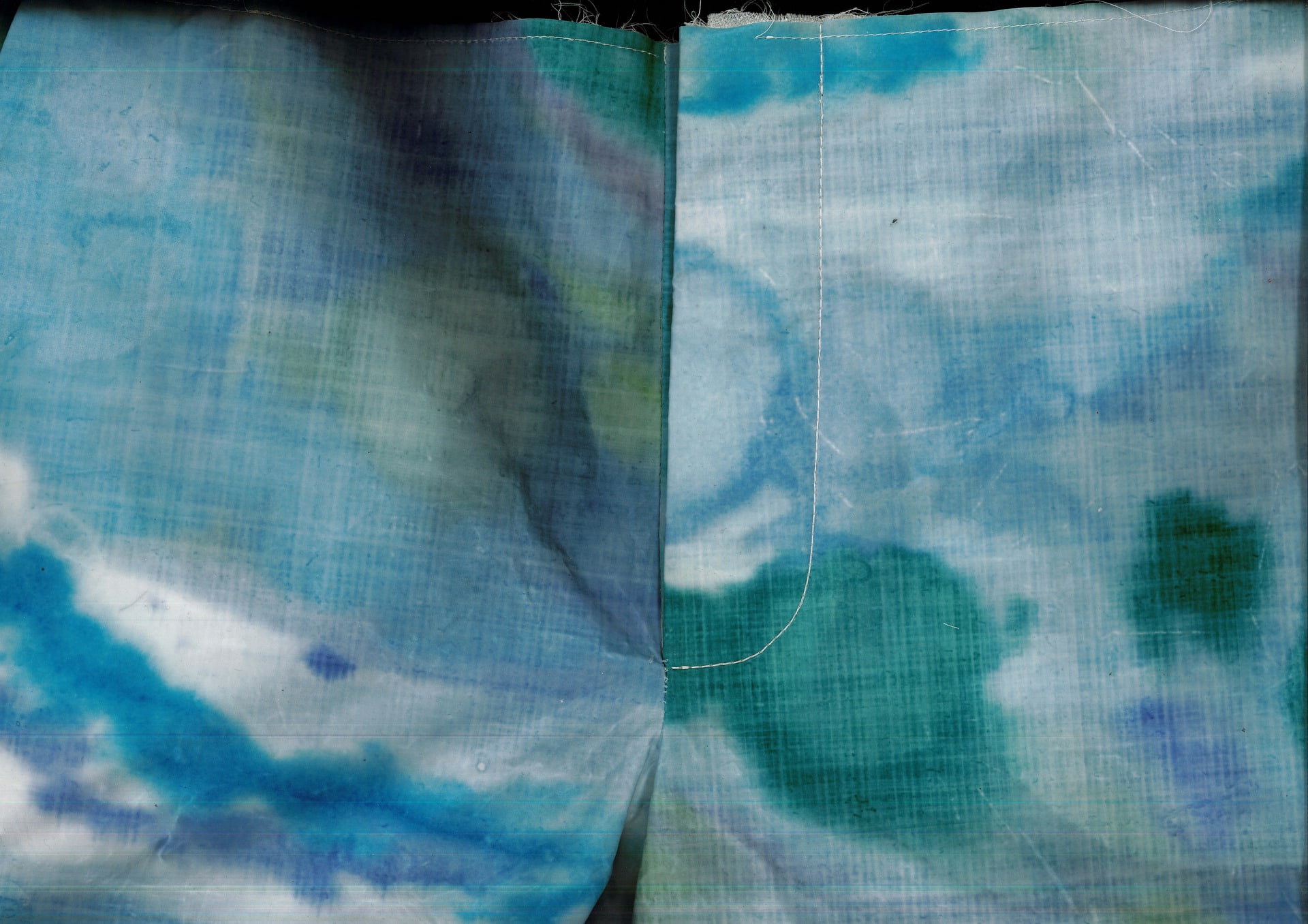 scanned image of menswear shorts, fabric has been monoprinted in colours of blue/green and then been waxed. 