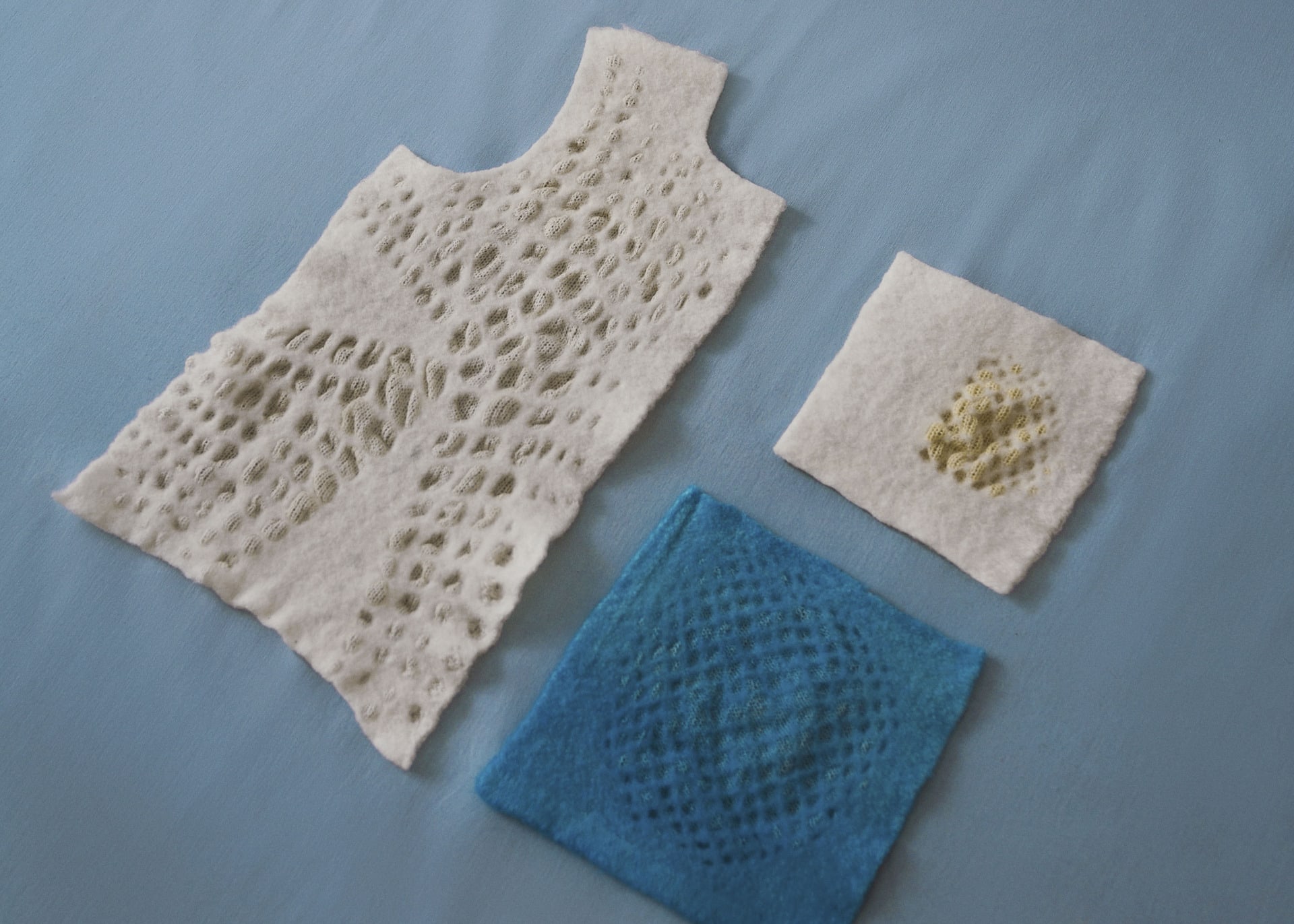 knitted samples of a resist forming a bodice panel blue circular piece, white quarter circle with bubbles of texture, on blue 