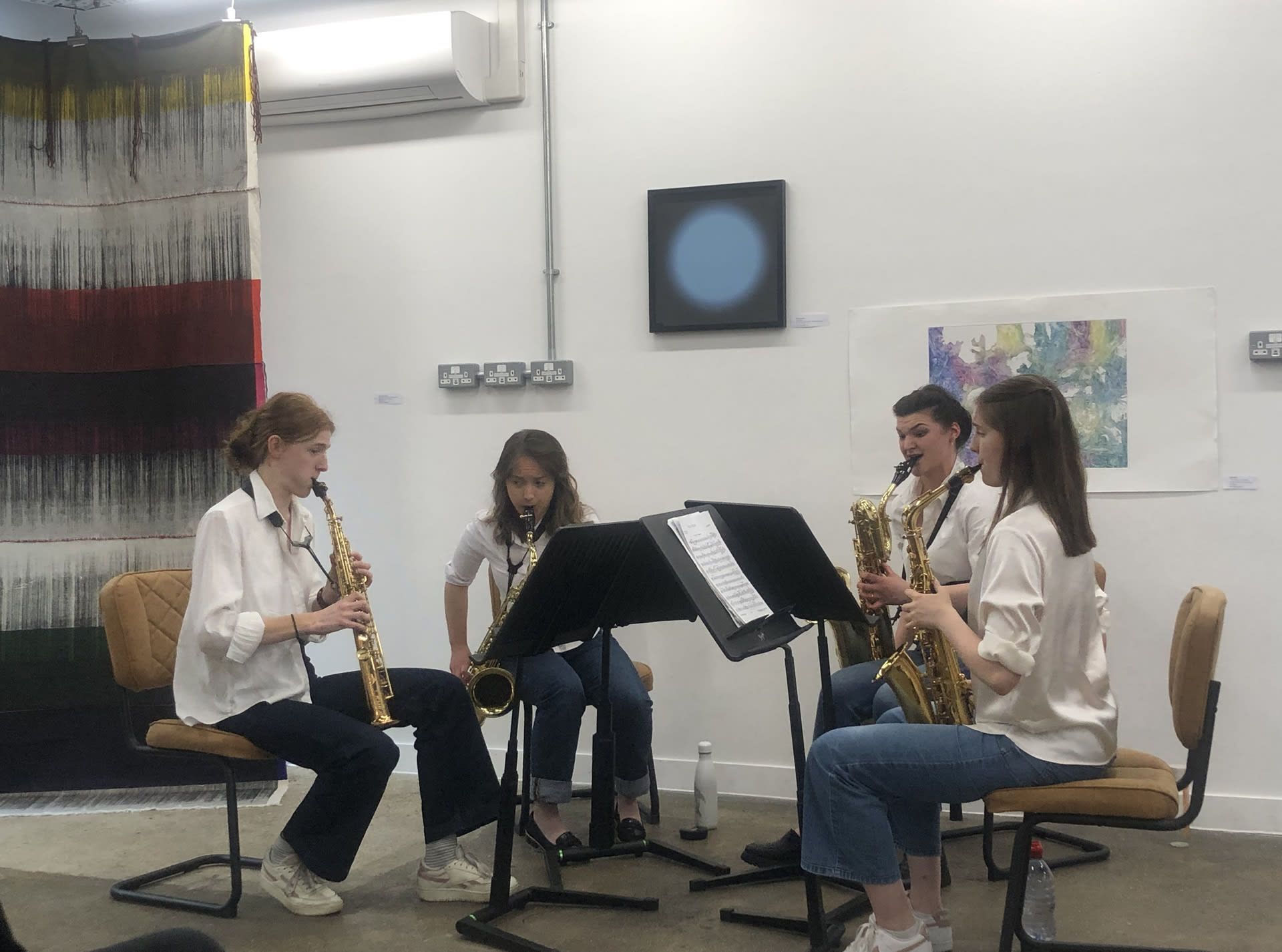 blue light on the wall in the background of a saxophone quartet playing