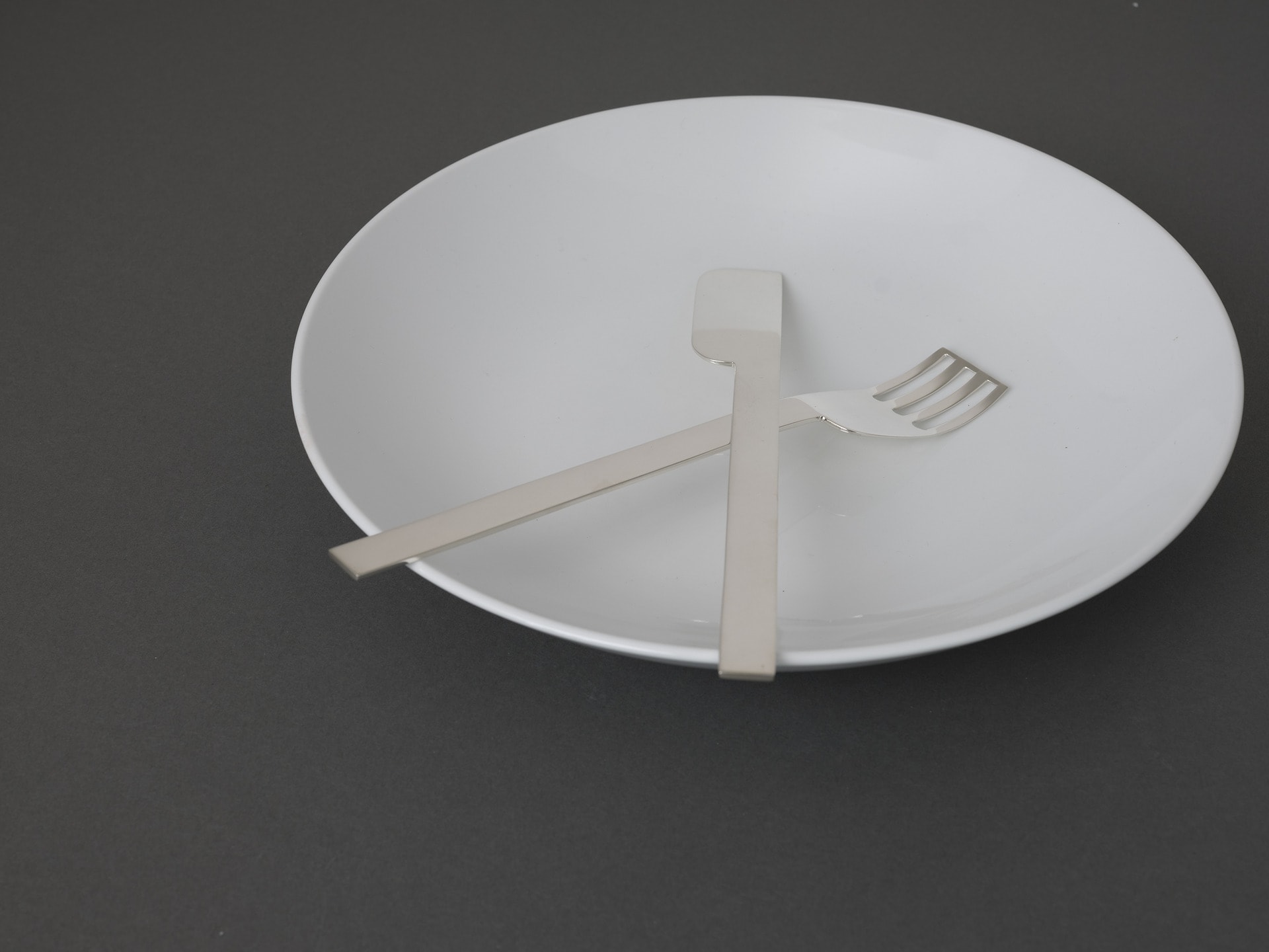 Hand forged sterling silver, knife and fork on a white ceramic plate