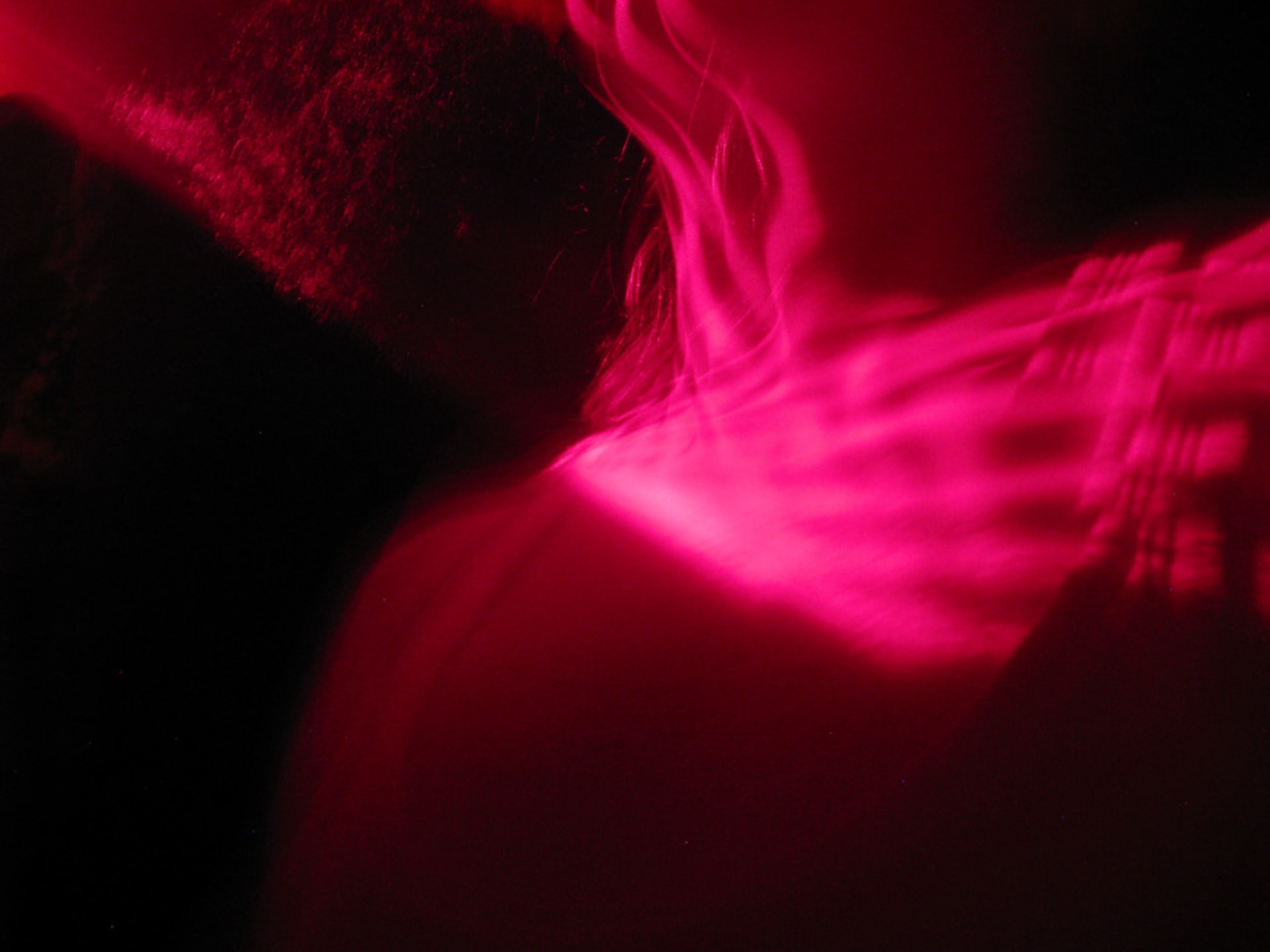 Red light refracted across the collar bones of a dancing torso