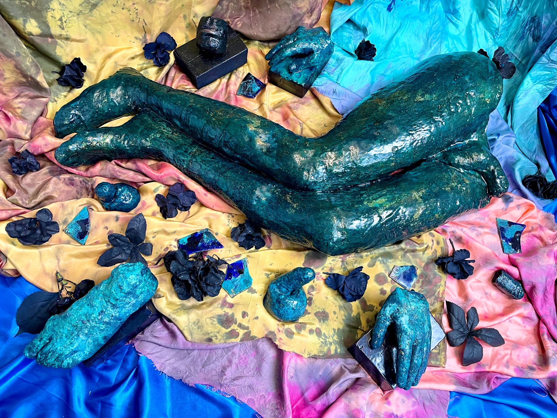 body fragments with artificial flowers placed on colourful hand dyed fabrics