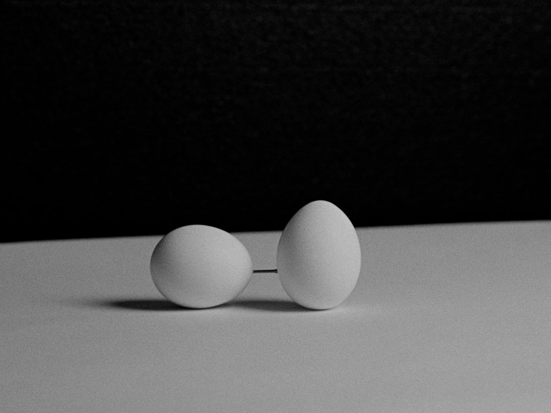 Two eggs linked by steel nails are placed on the table.