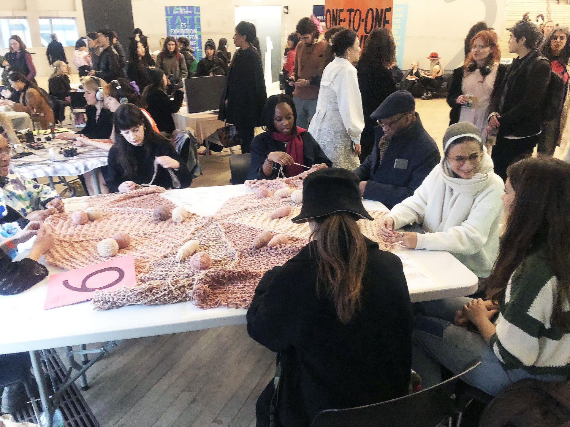 People sat around a table hand knitting 