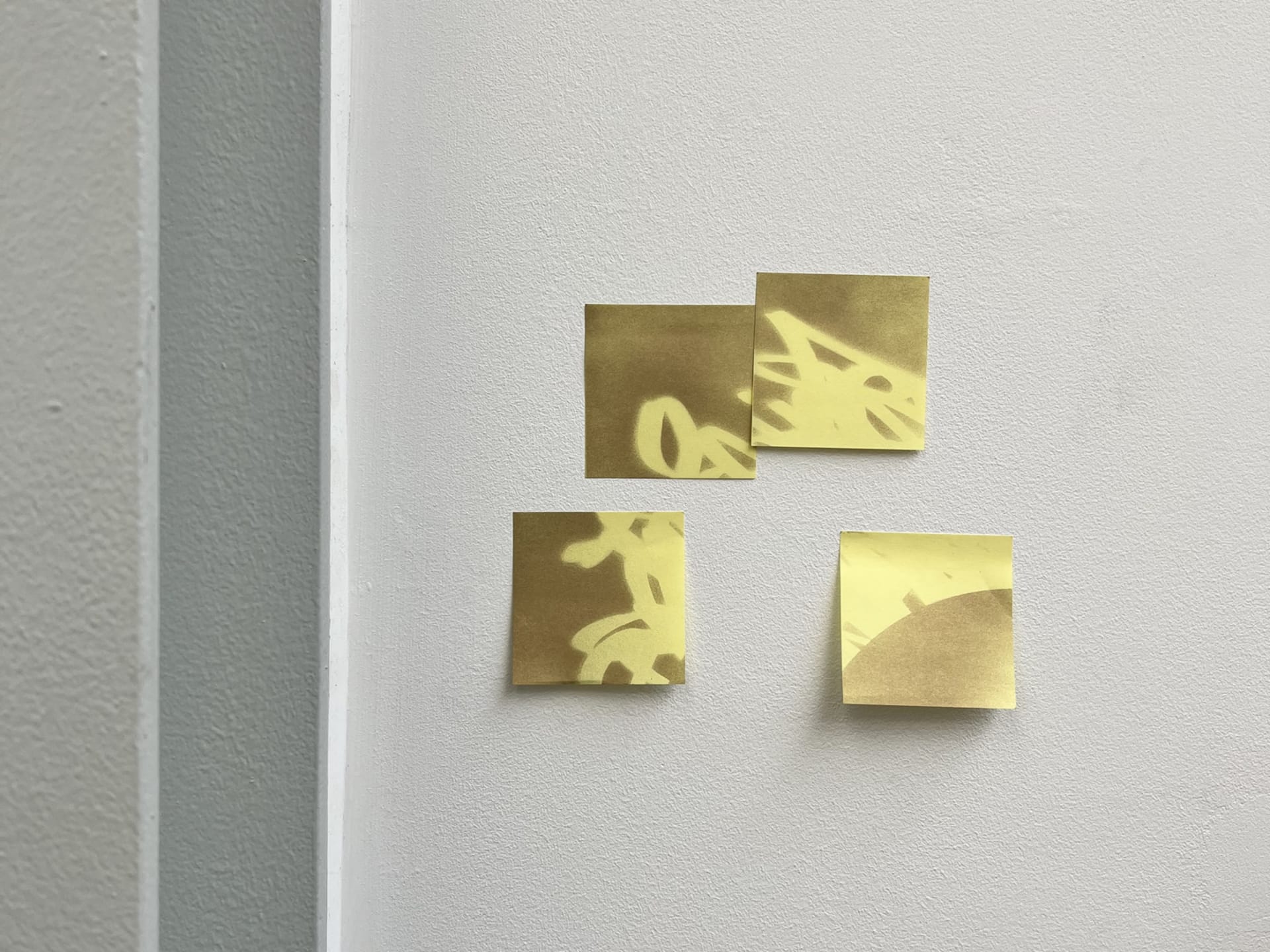 Post-it notes covered in graffiti affixed to a wall. 