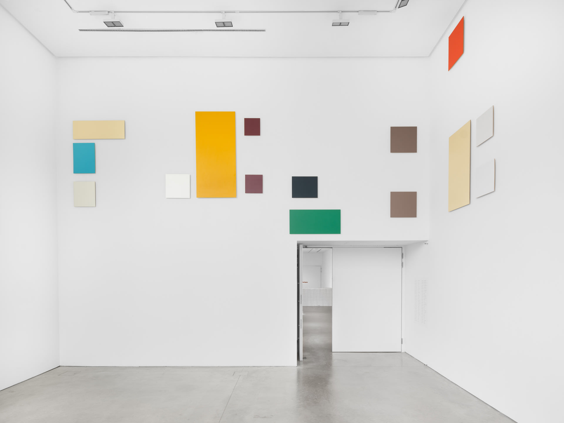 An assortment of geometric shapes installed above eye level in a white gallery space.