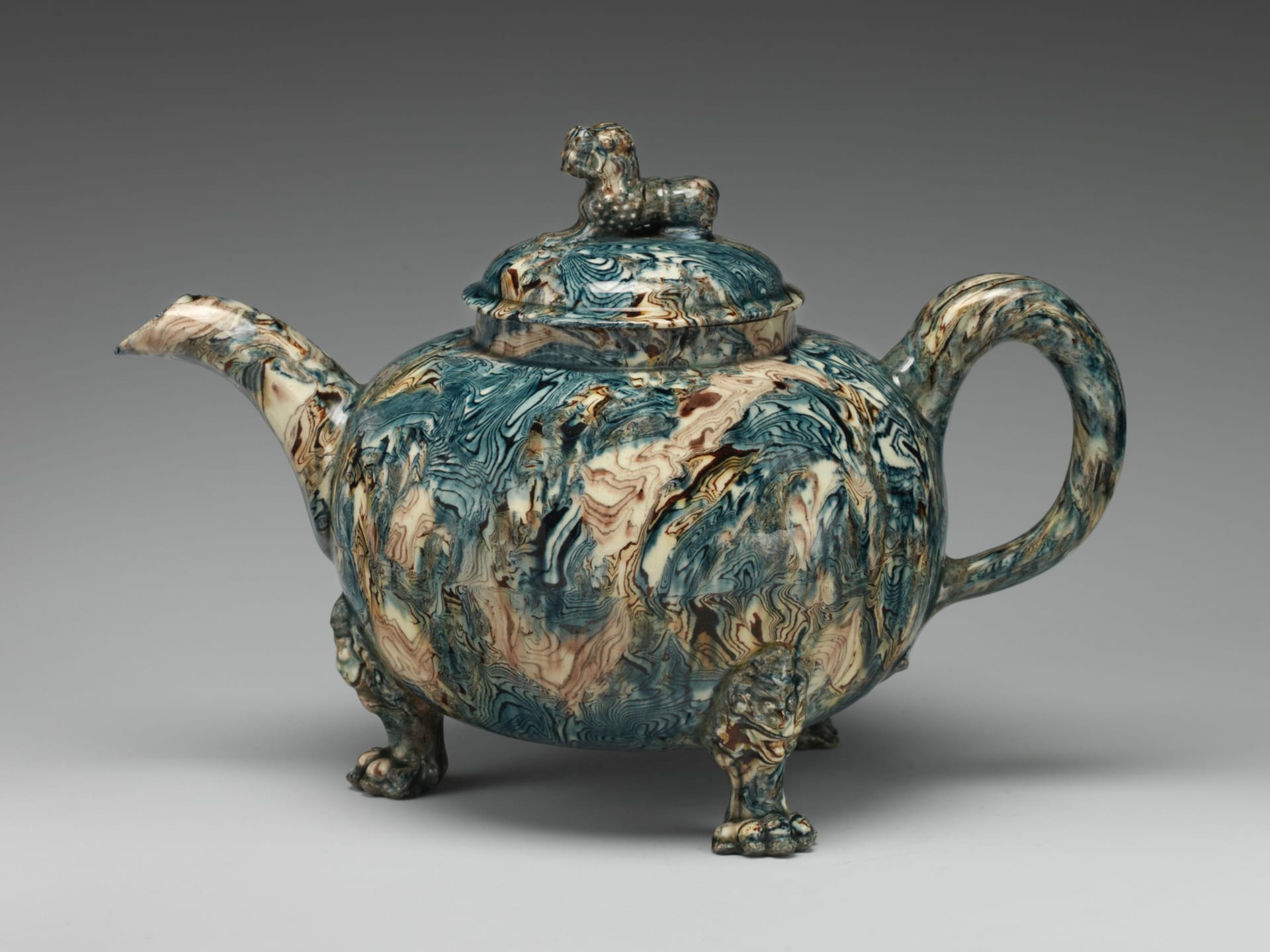 A three-footed agateware teapot, made from blue and brown clays, with a knop in the shape of a Chinese lion