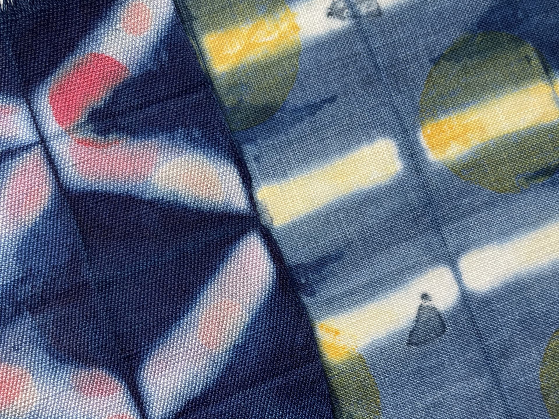 2 Mono-printed Indigo samples. 1st one has a diamond design with pink circles. 2nd one has a stripe pattern with yellow circles.