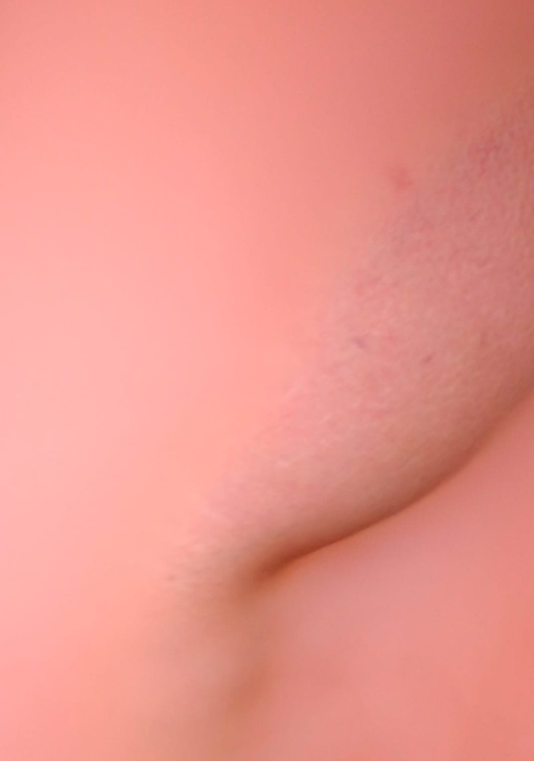 A flesh tone textured image resembling part of a body coming out of a flat fleshy surface.