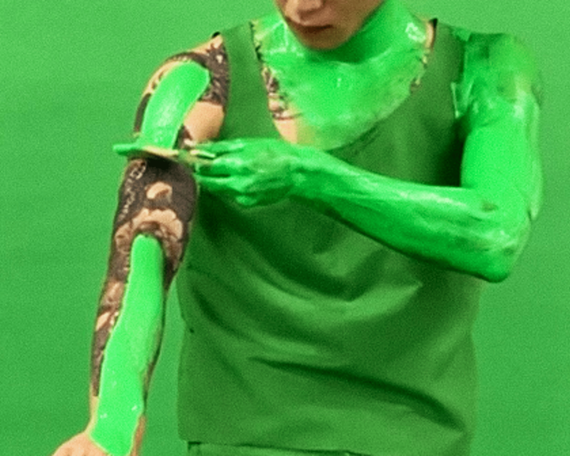 A person is painting his body with chroma key effect green colour.