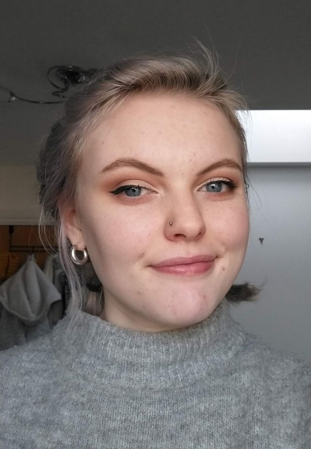 Photograph of Melissa Spreadborough - a young white woman with blue eyes and light hair, wearing a grey jumper