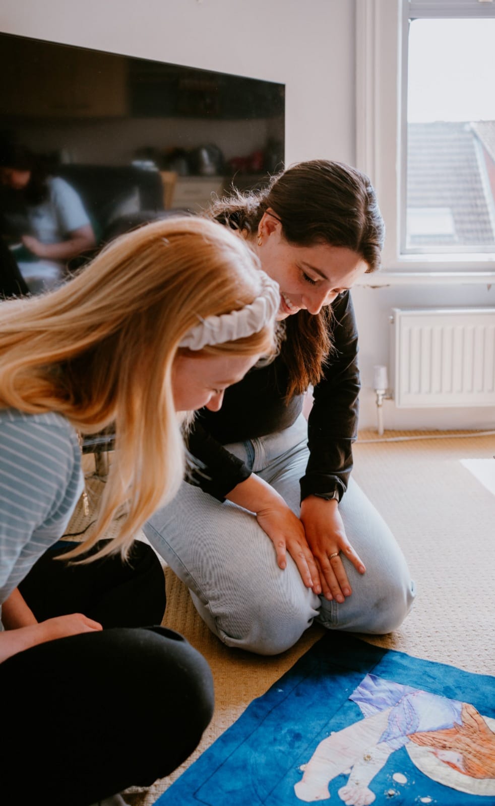 Two woman looking at an embroidery piece