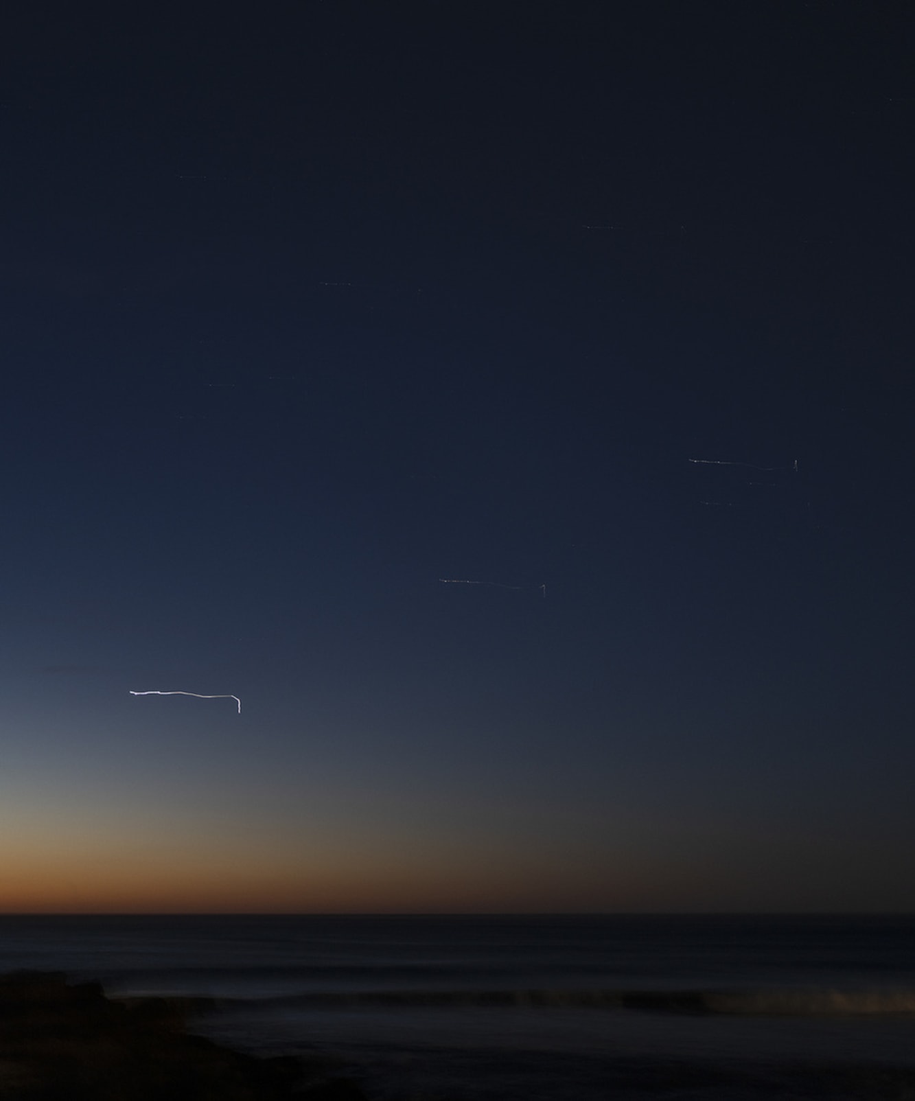 Thin streaks of light above a horizon line over the ocean, before sunrise