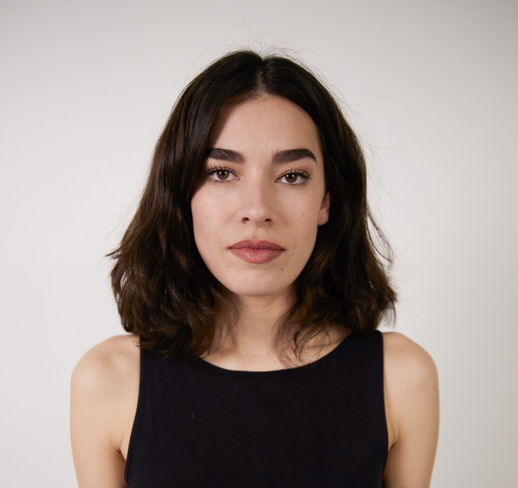 Portrait of a young white woman with dark brown short hair and dark brown eyes. 