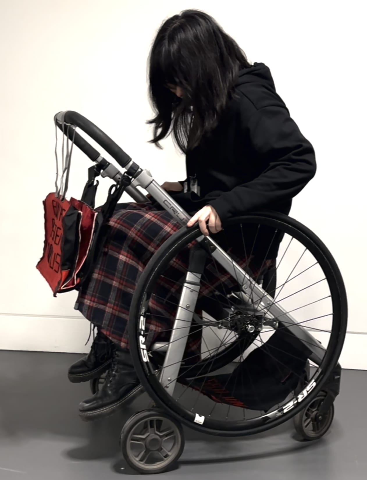 Joy, a young east asian woman and the designer and maker of the object, is sitting in and interacting with the project