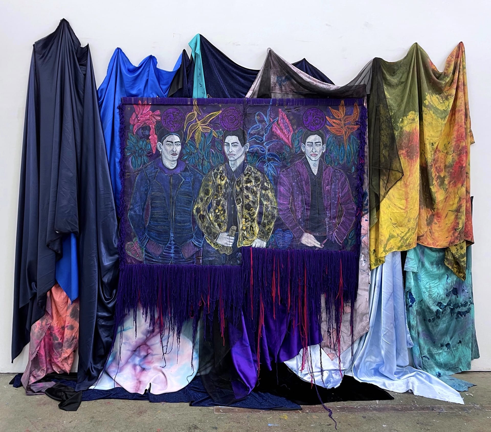 Installation on the wall, with heavy fabrics and a painting tapestry with three male figures