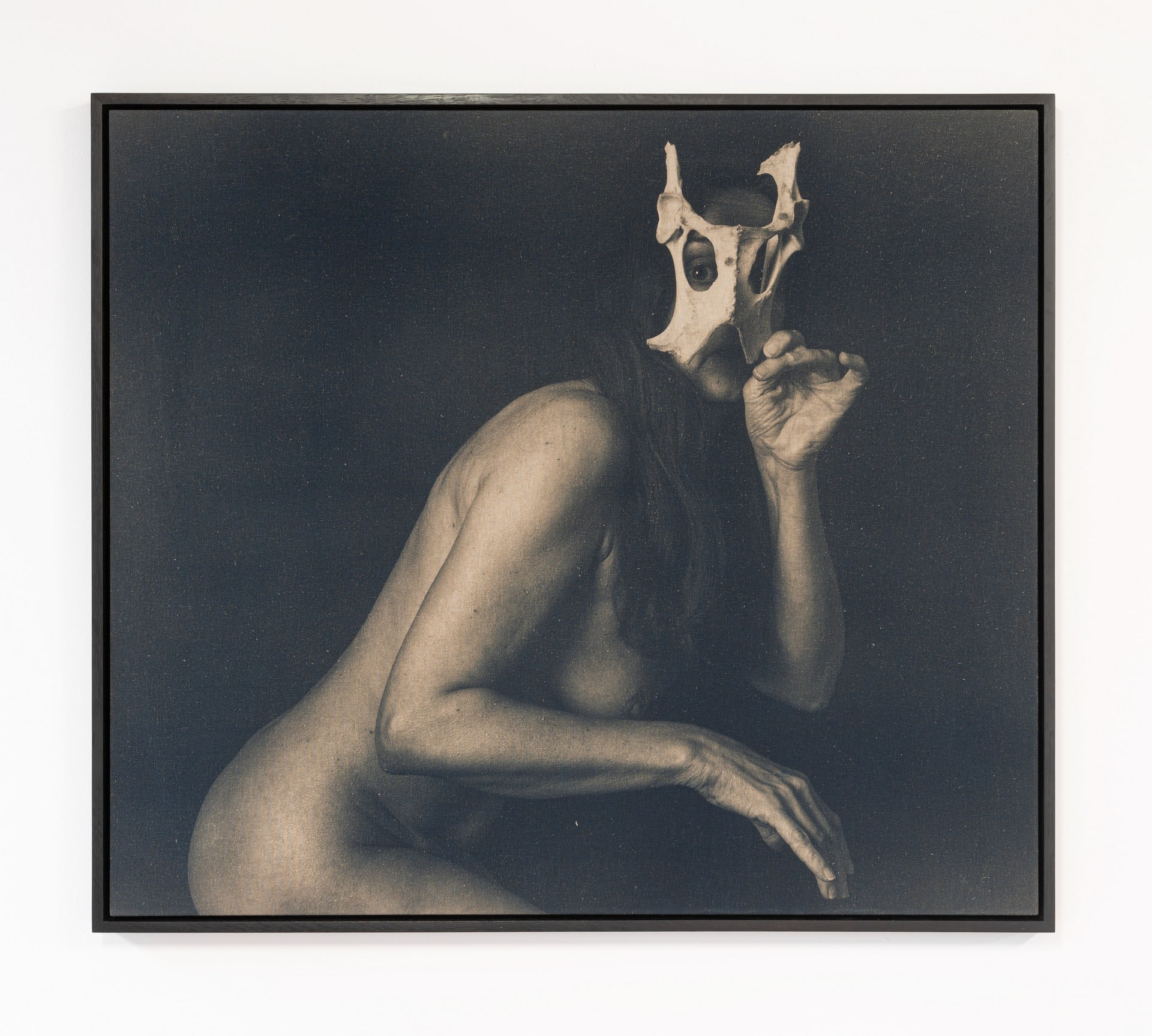 A woman pretending to be a deer, holding up a deer pelvis as a mask