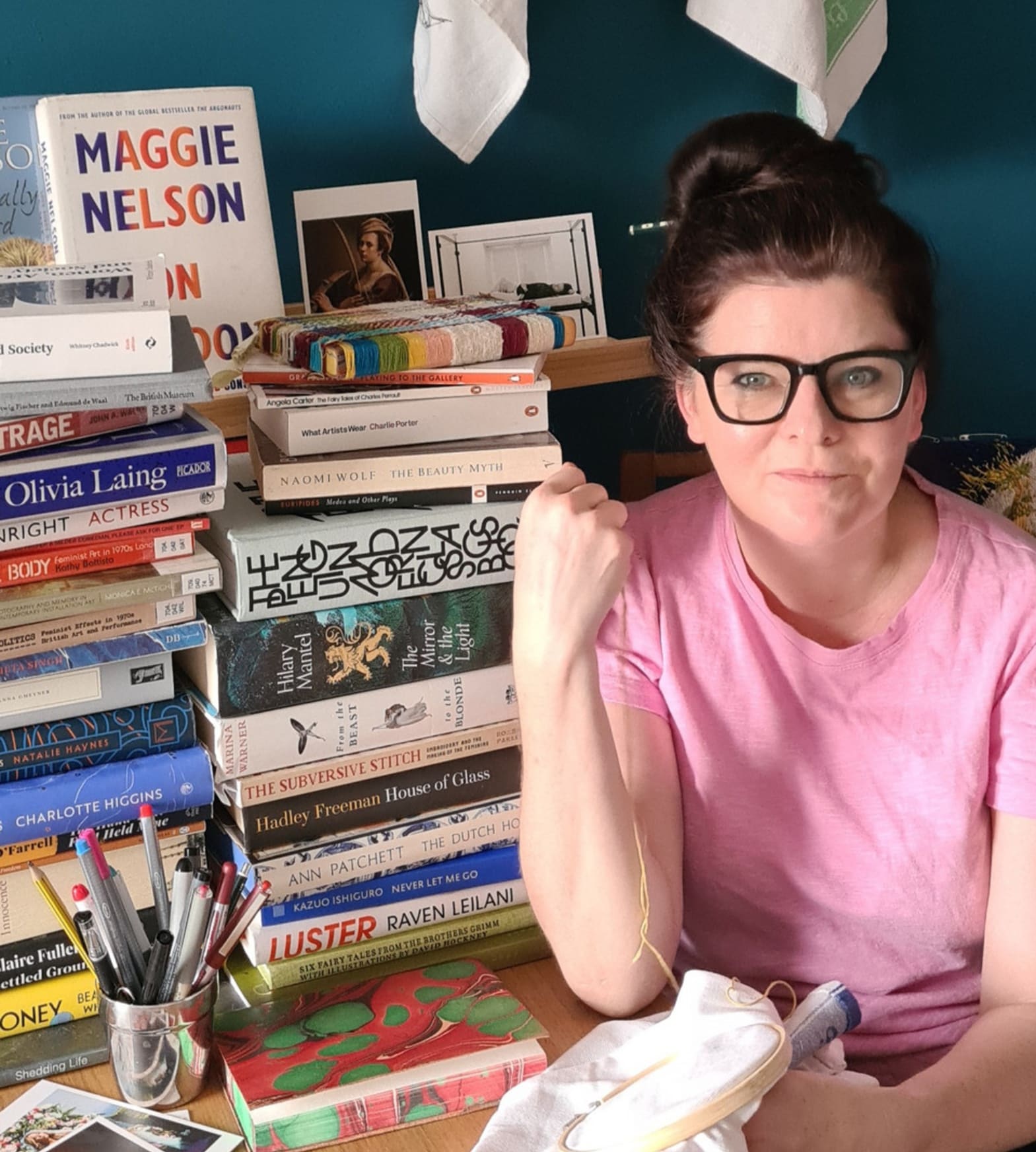 Picture of the artist in her studio space surrounded by books and textiles