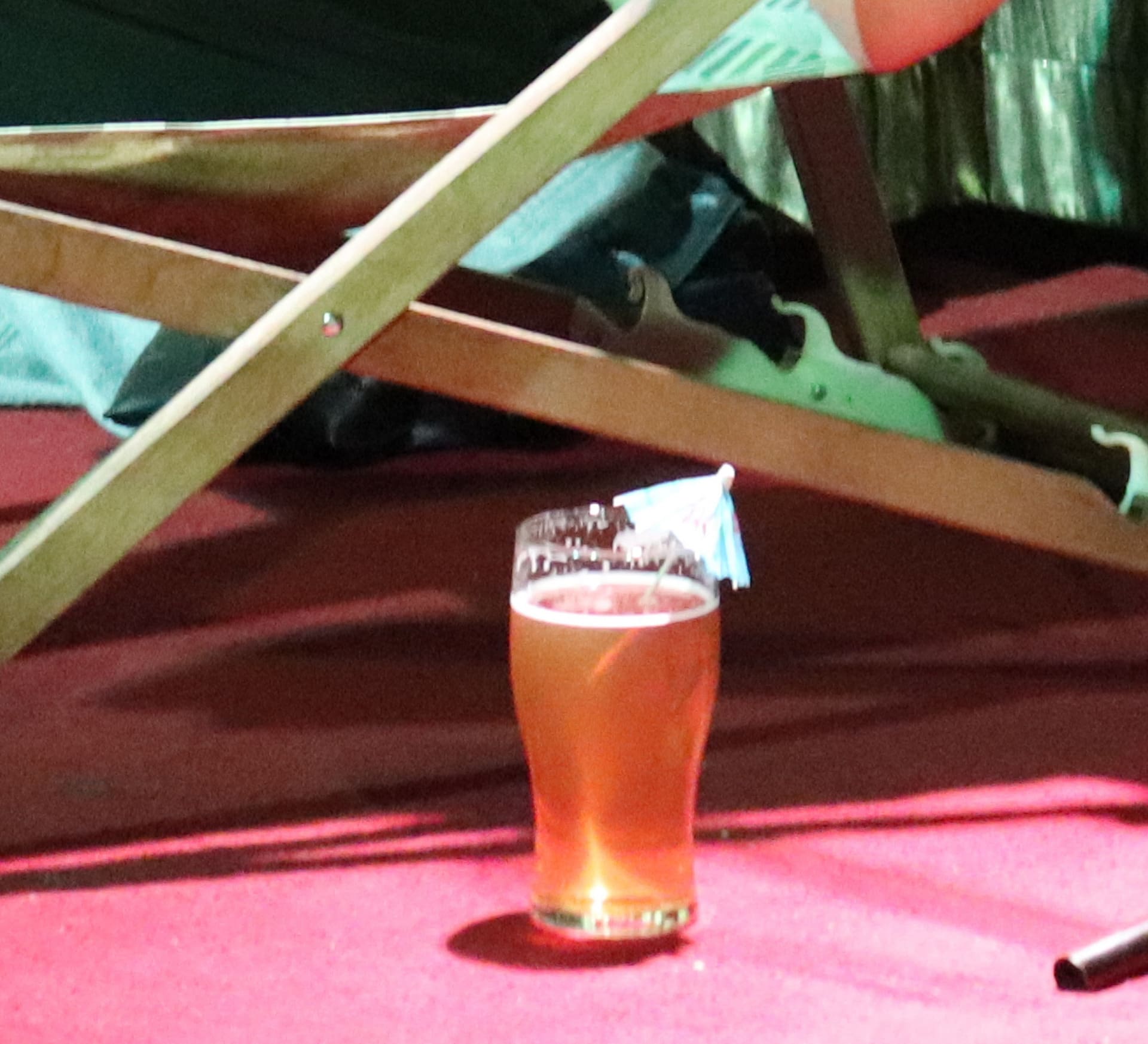 A photo of a pint of beer on a stage with a cocktail umbrella in it. 