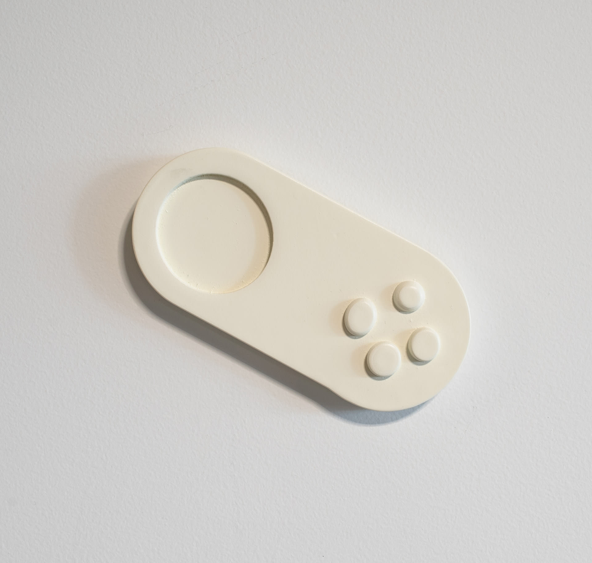 Cream wall-mounted sculpture, pill-shaped with controls.