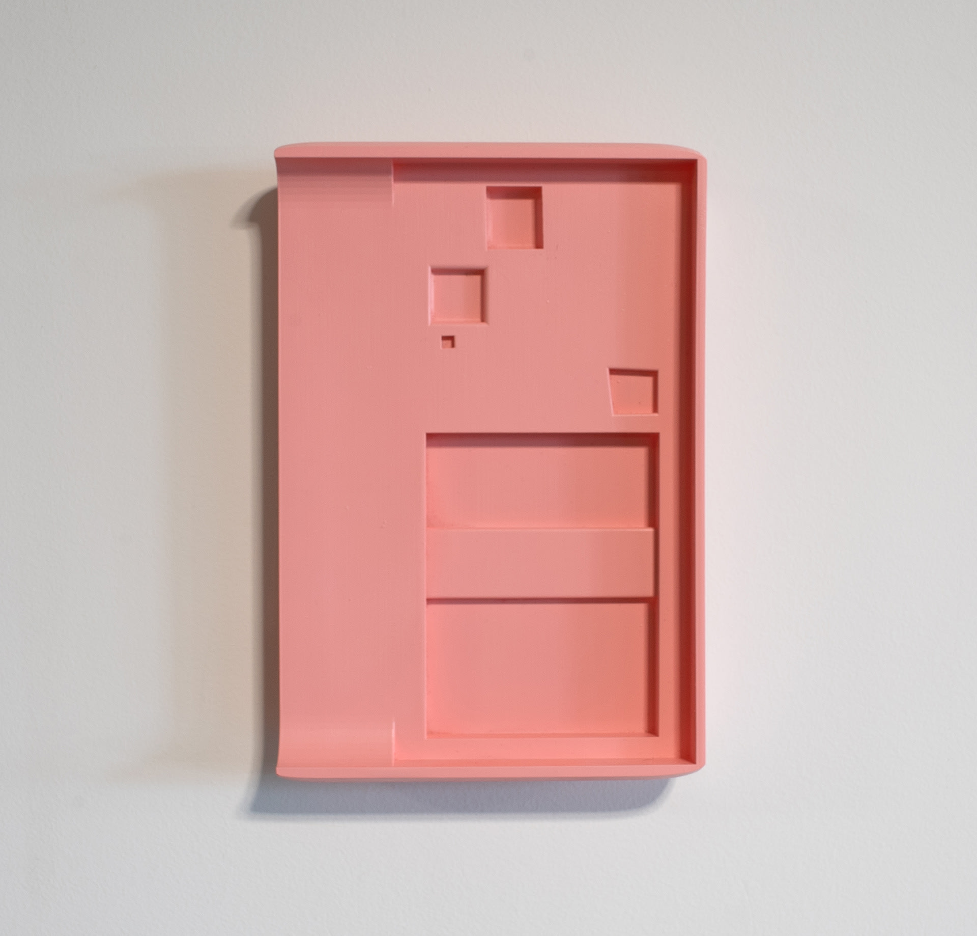 Pink wall-mounted sculpture, rectangular with curved sides and square indentations. 