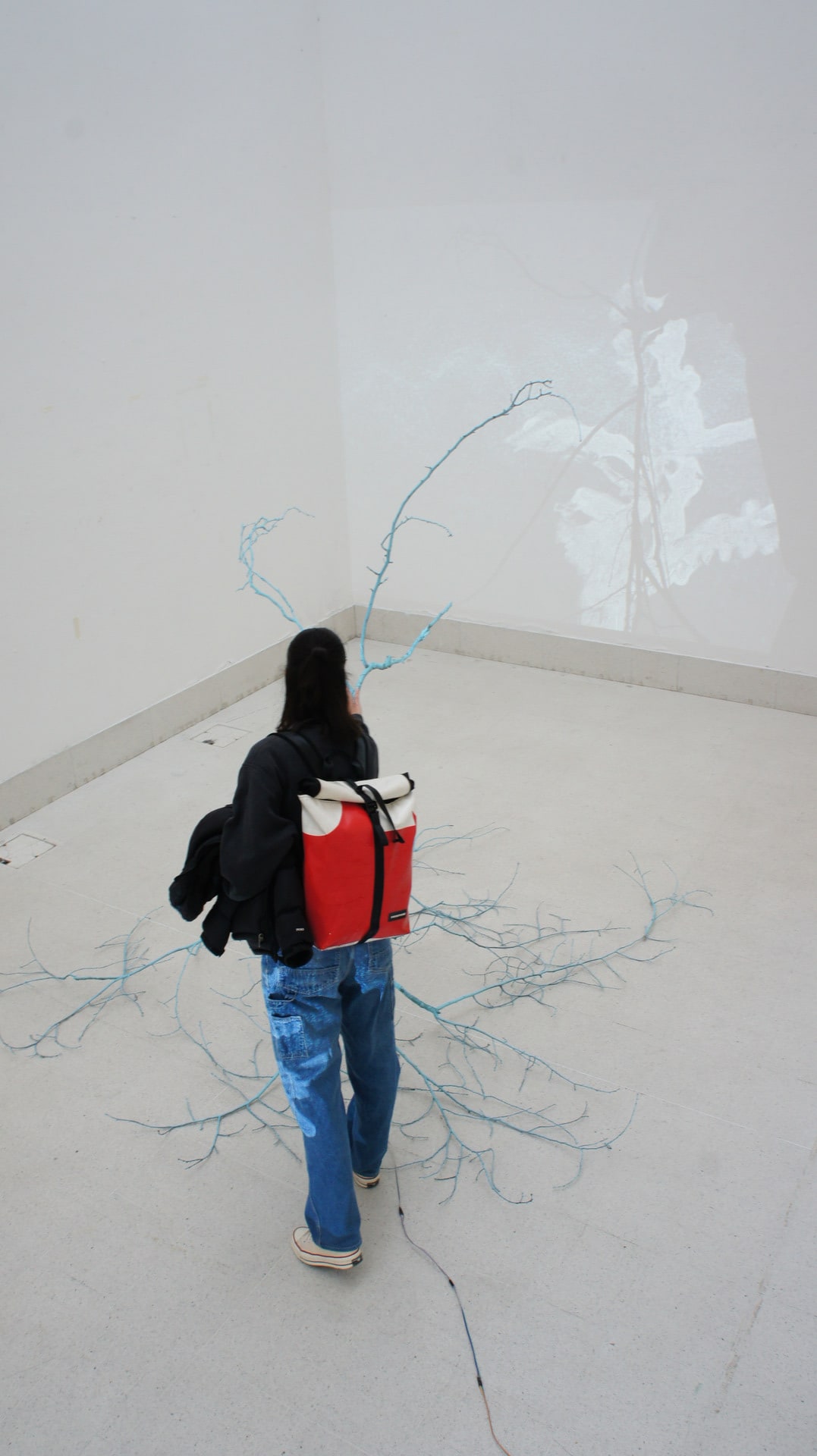 Visitor with a red backpack interacting with the sculpture; image taken from above. 