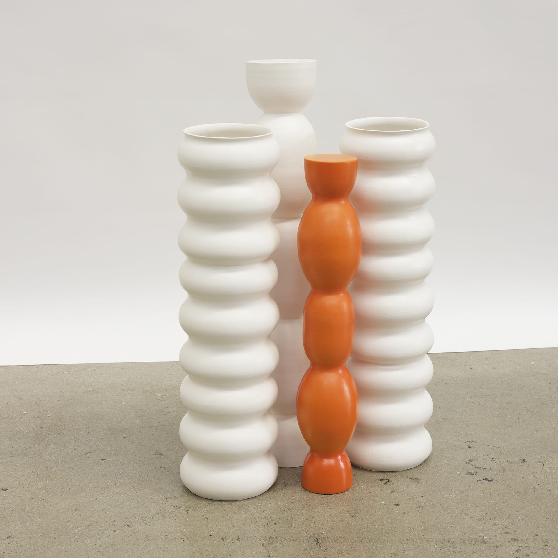 Wobbly tall vessels of slightly different shapes. Smooth appearance and a shiny surface