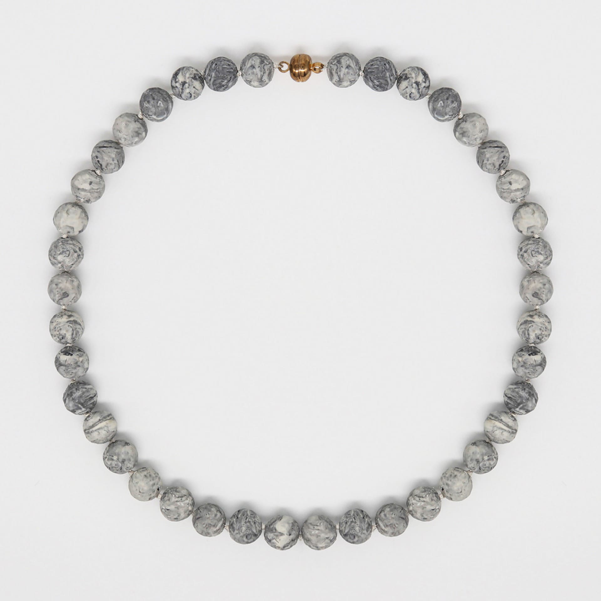 A round necklace made of beads formed from erased text.