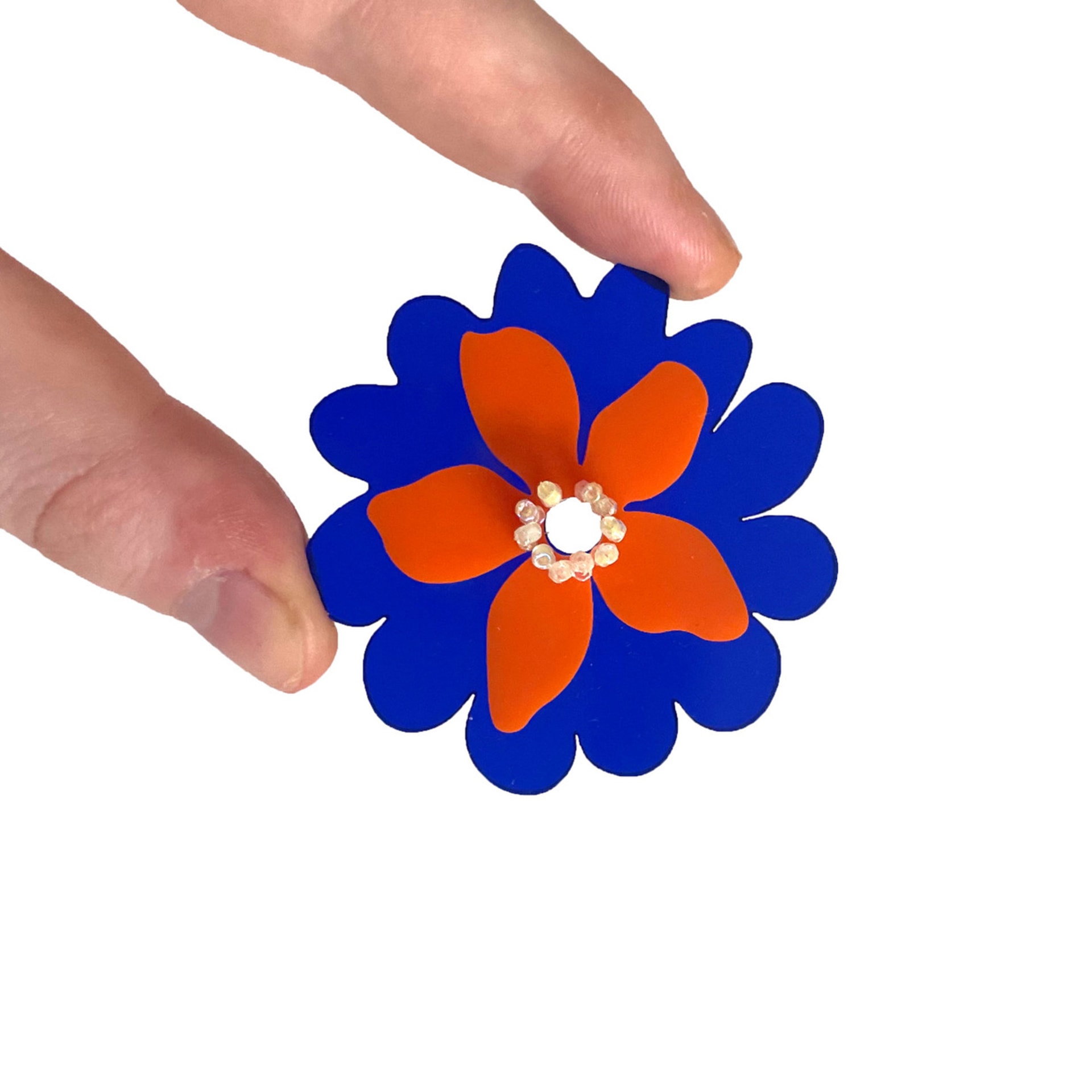 Abstract flower motif laser cut out of acrylic plastic. Two layers to this shape, the back royal blue, the front burnt orange.