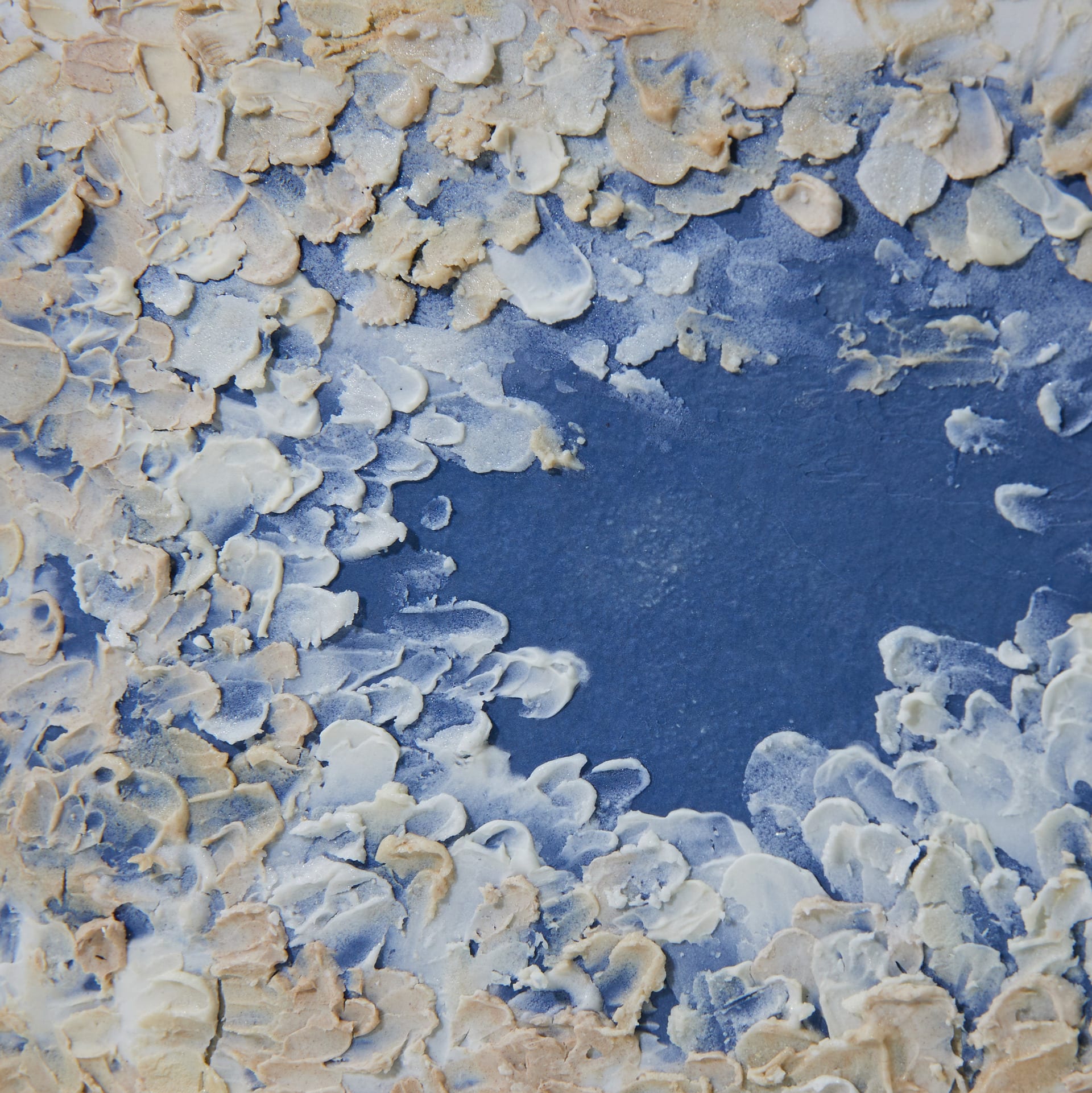 blue surface covered with white and beige clay or glaze.