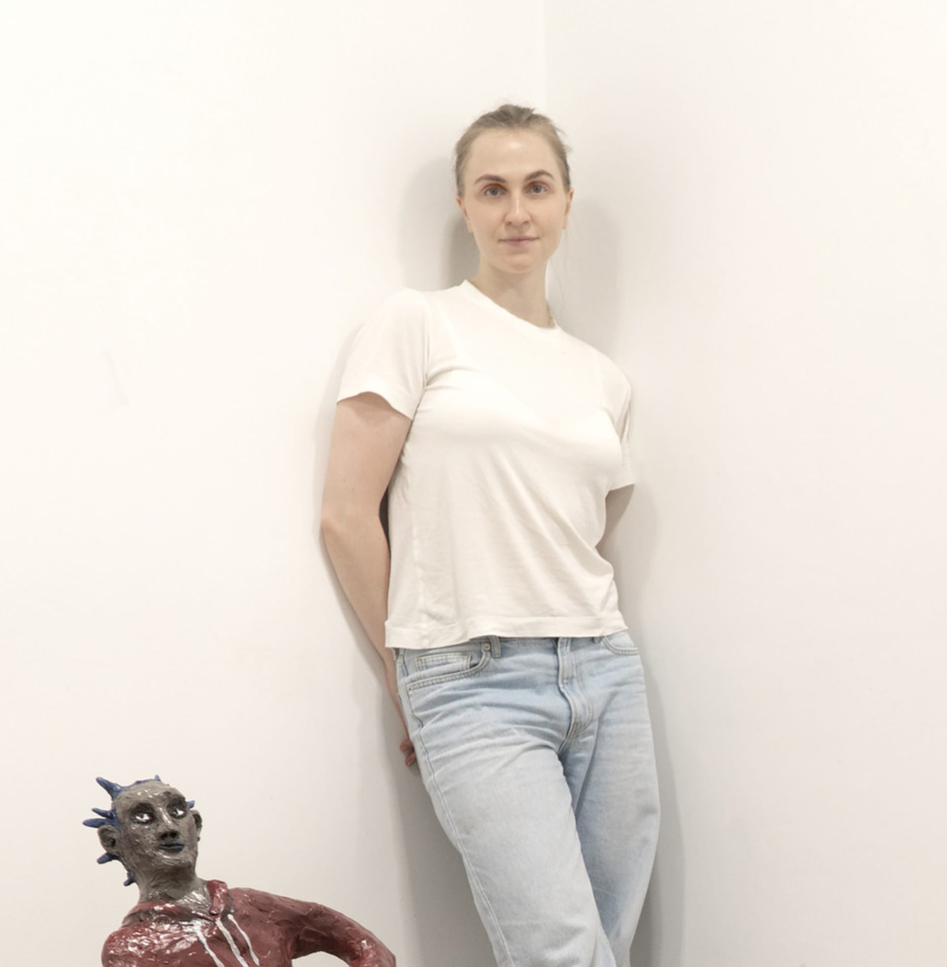 Woman leaning against wall in white t-shirt and light blue jeans