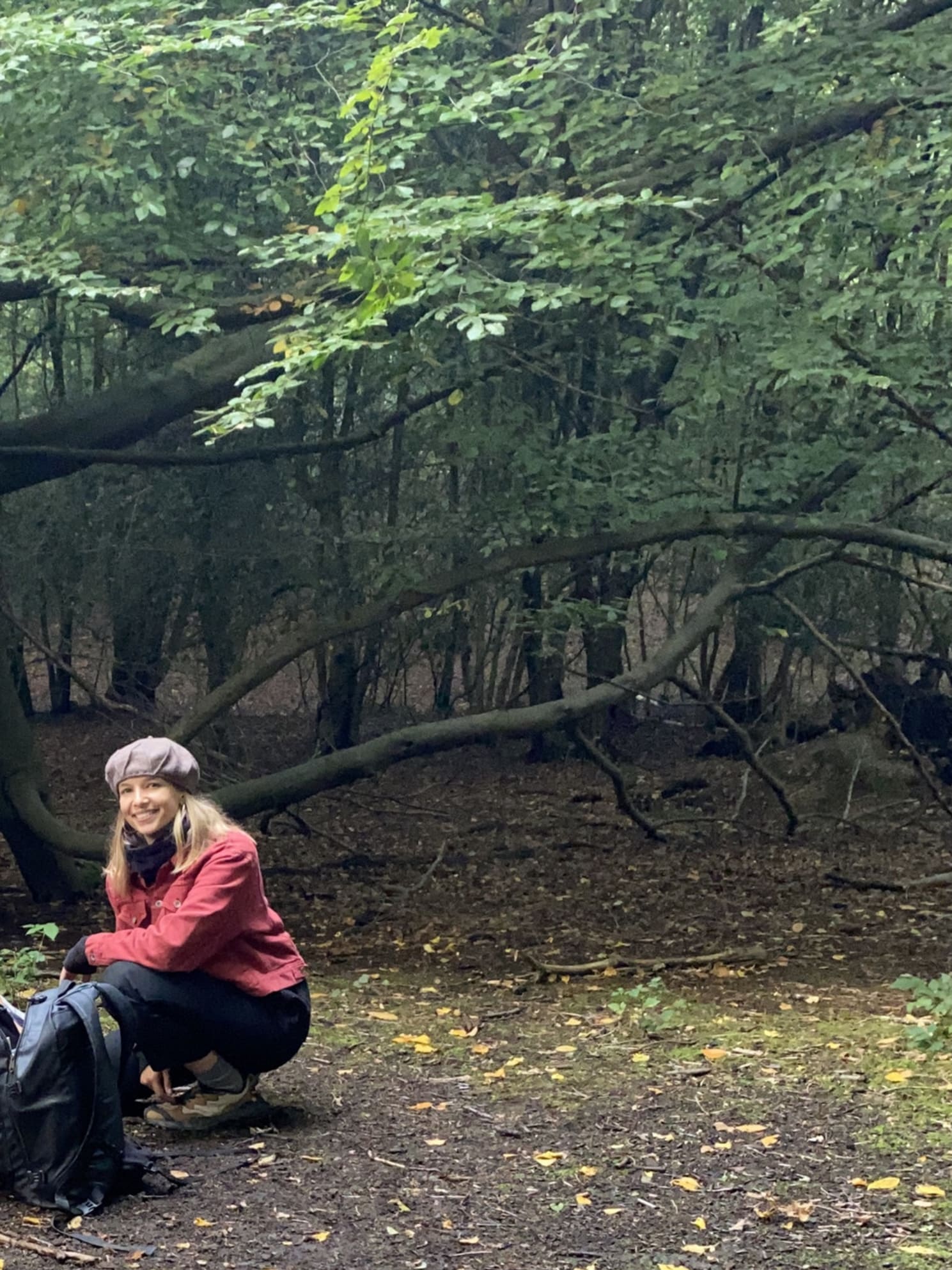 Emma kneels by a tree under a canopy of green leaves in magical Epping Forest.