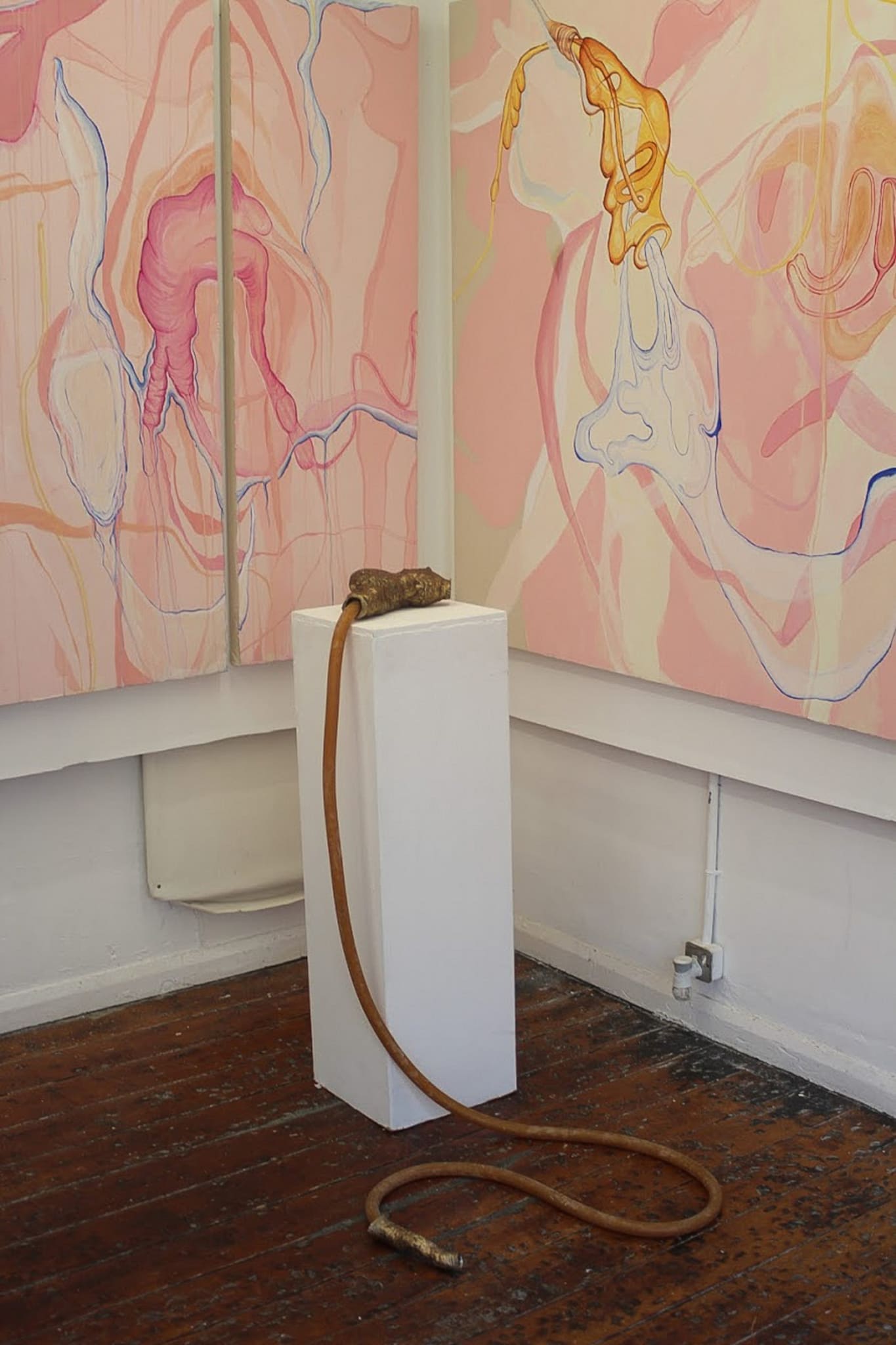 intersection of two paintings behind a bronze vessel sculpture displayed on a pedestal 