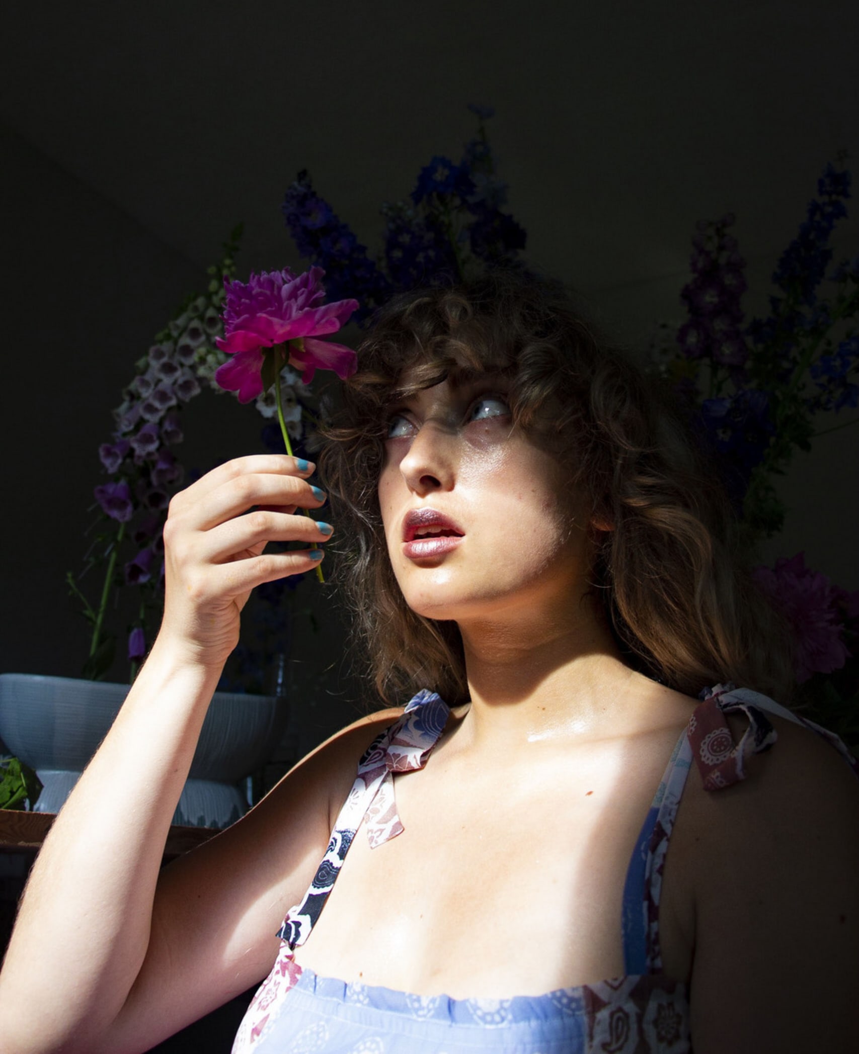 Finan Malcolm. A self-portrait from her photography practice, holding a peony up to her eyes, looking at it in wonderment. 