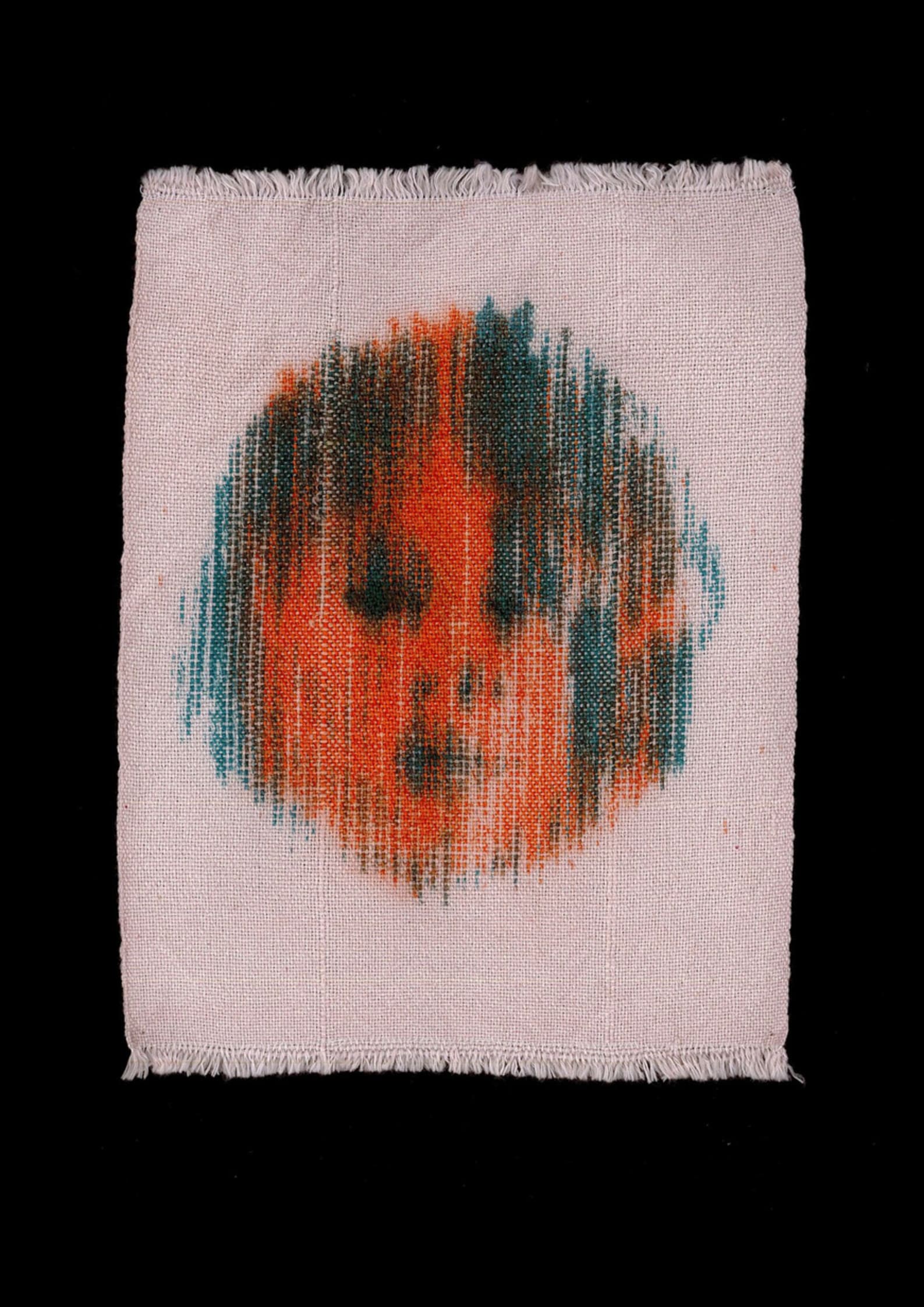 a photograph of a small rectangle of handwoven cloth on a black background. The cloth is light pink, and woven into it is a face