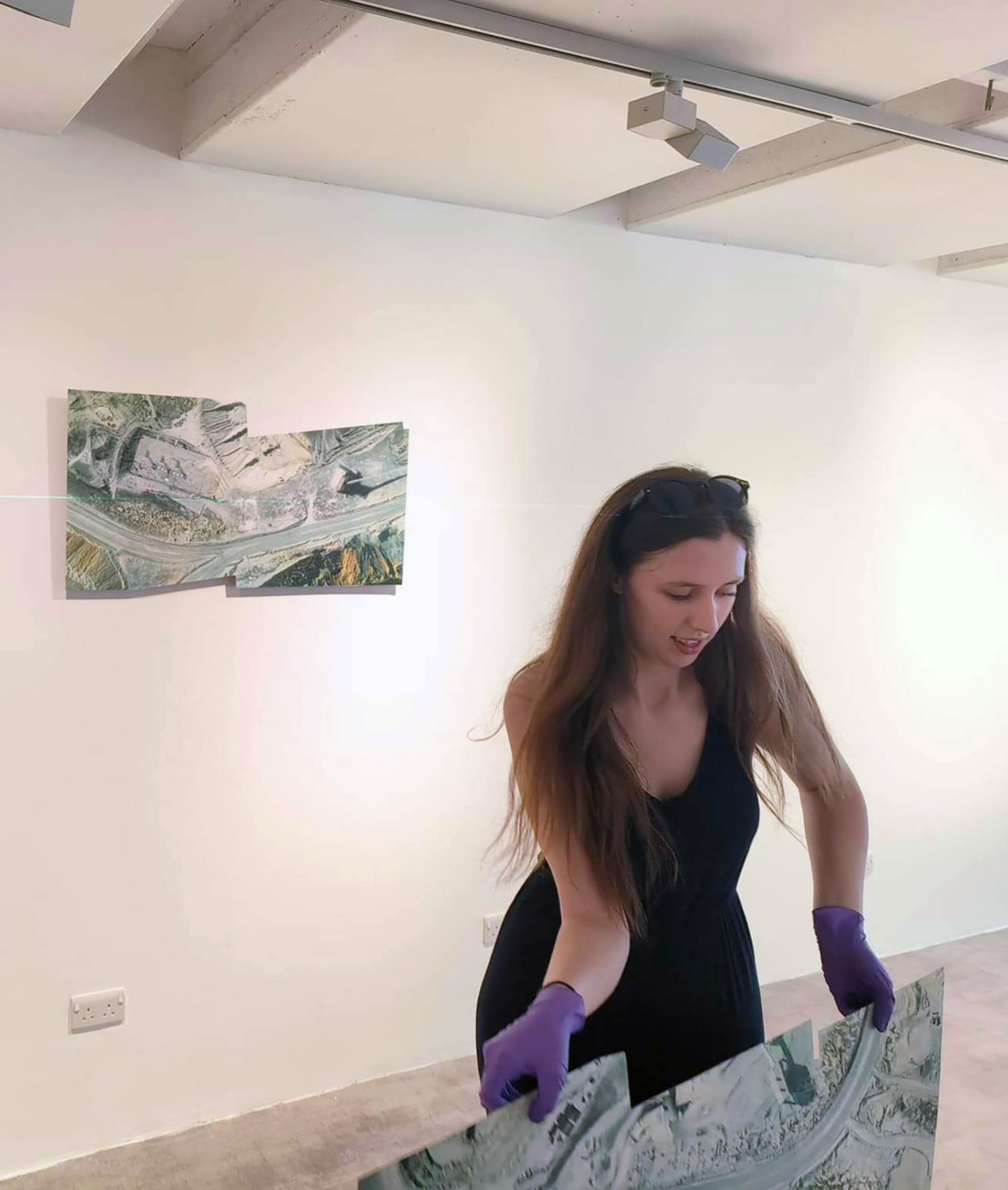 Anna holding a screen print during install in a gallery.