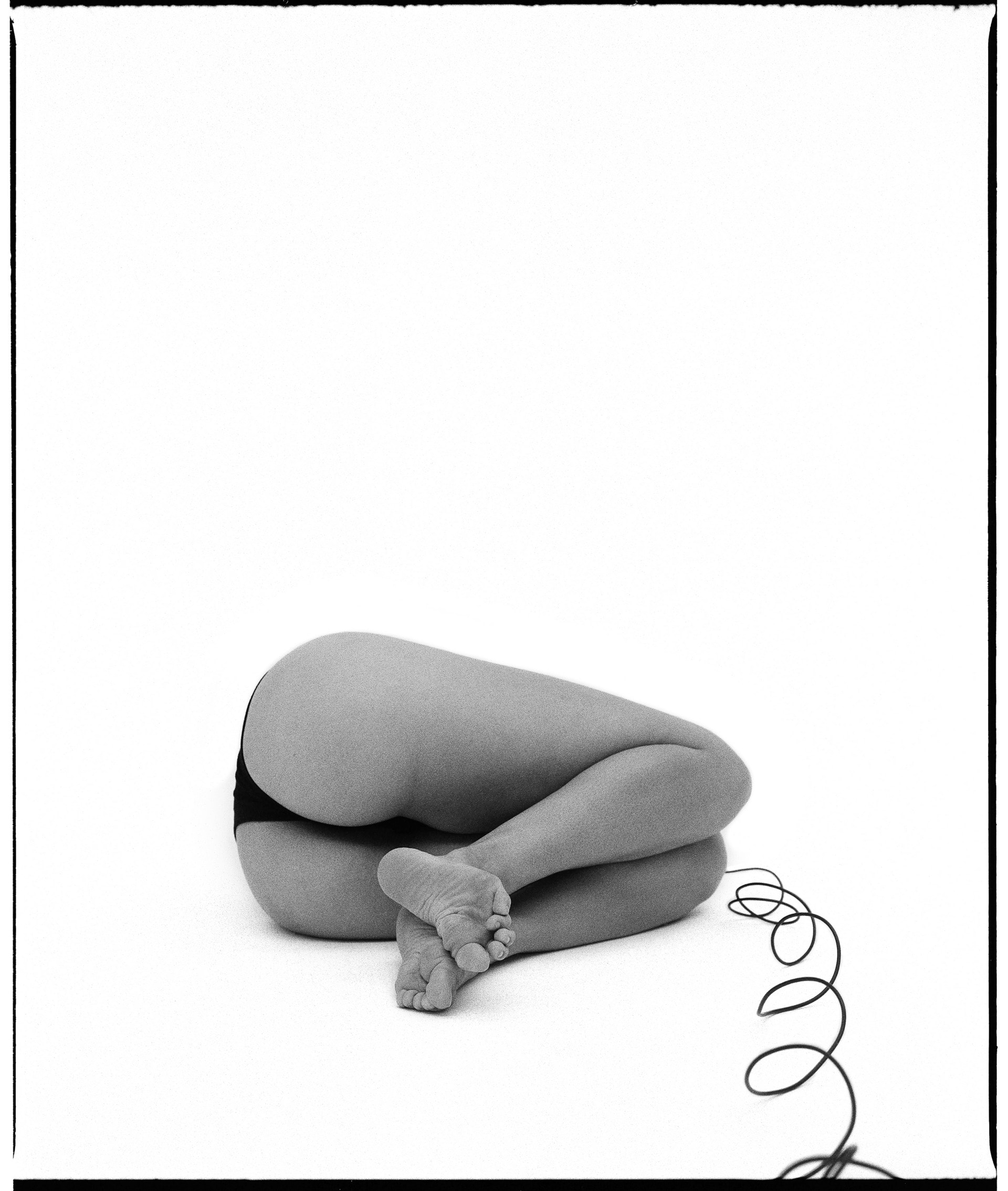 black and white self-portrait laying on side with legs up, faced away from the camera