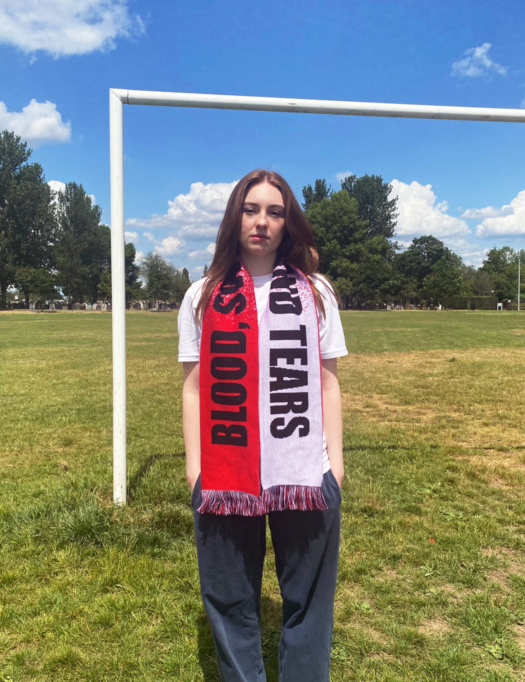 Model wearing Blood, Sweat and Tears scarf on football pitch.