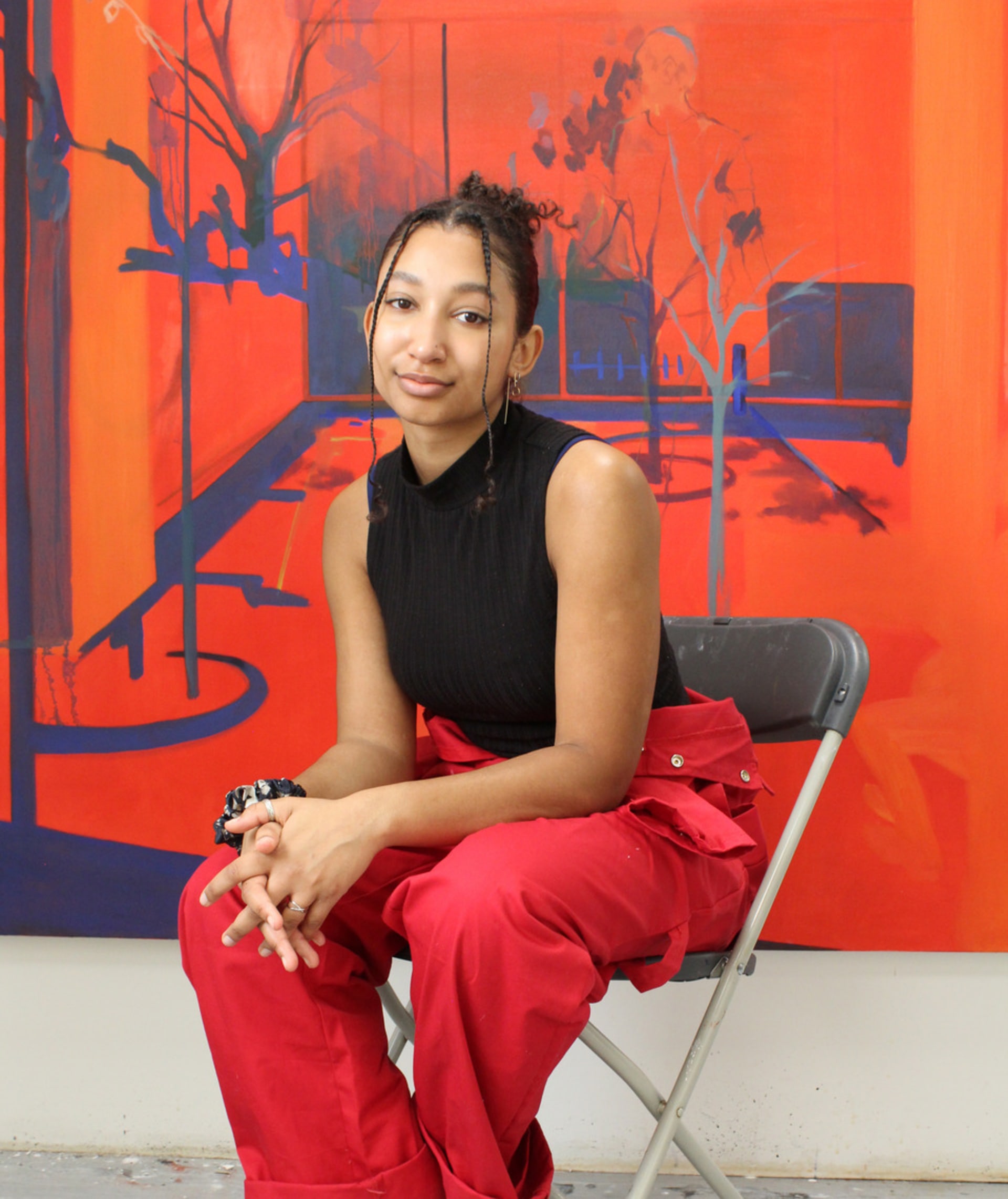 Hettie Inniss, sitting in her studio in front of painting "Clawing At the Truth" (2023)