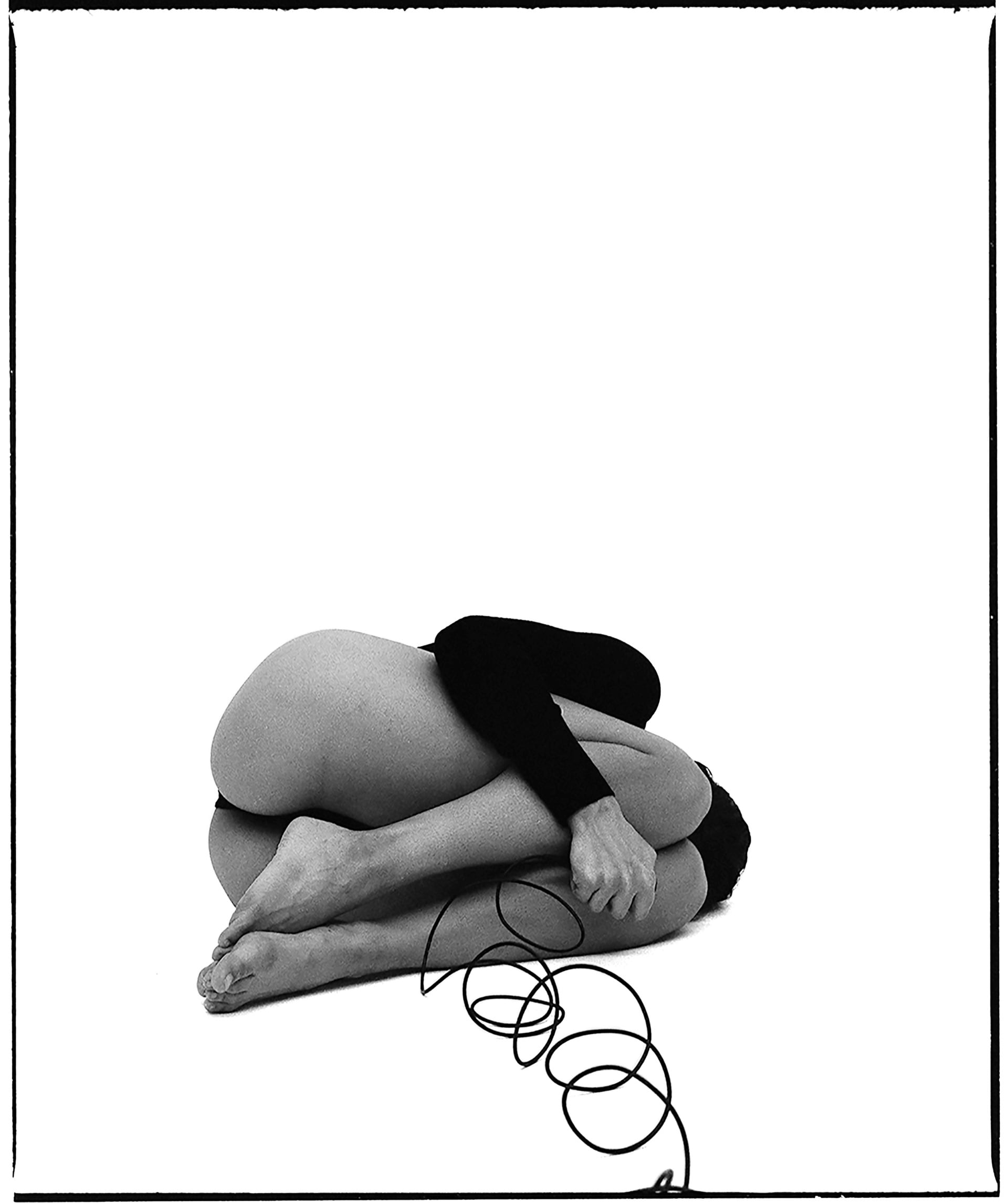 black and white self-portrait, curled up in a foetal position with face hidden from the camera