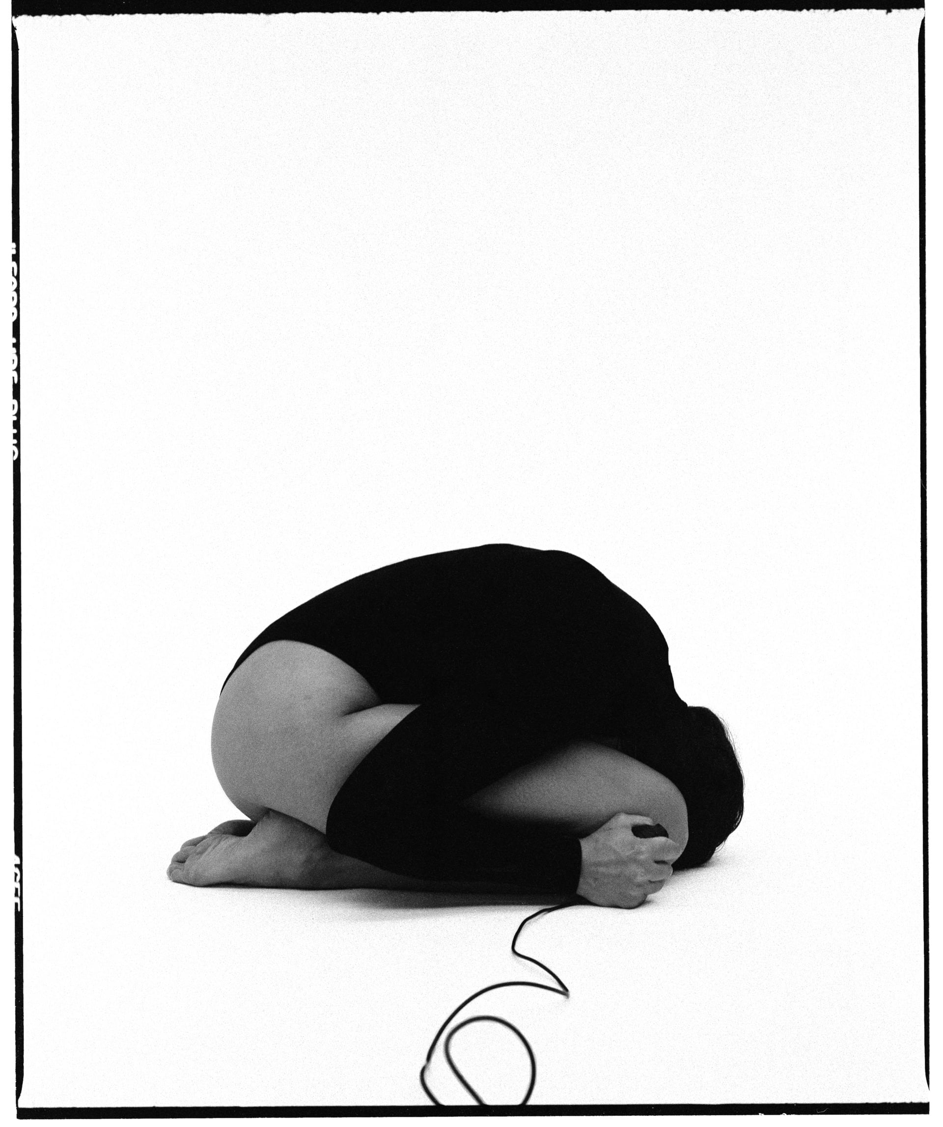 black and white self-portrait, curled up in a ball, facing sideways, face hidden from the camera