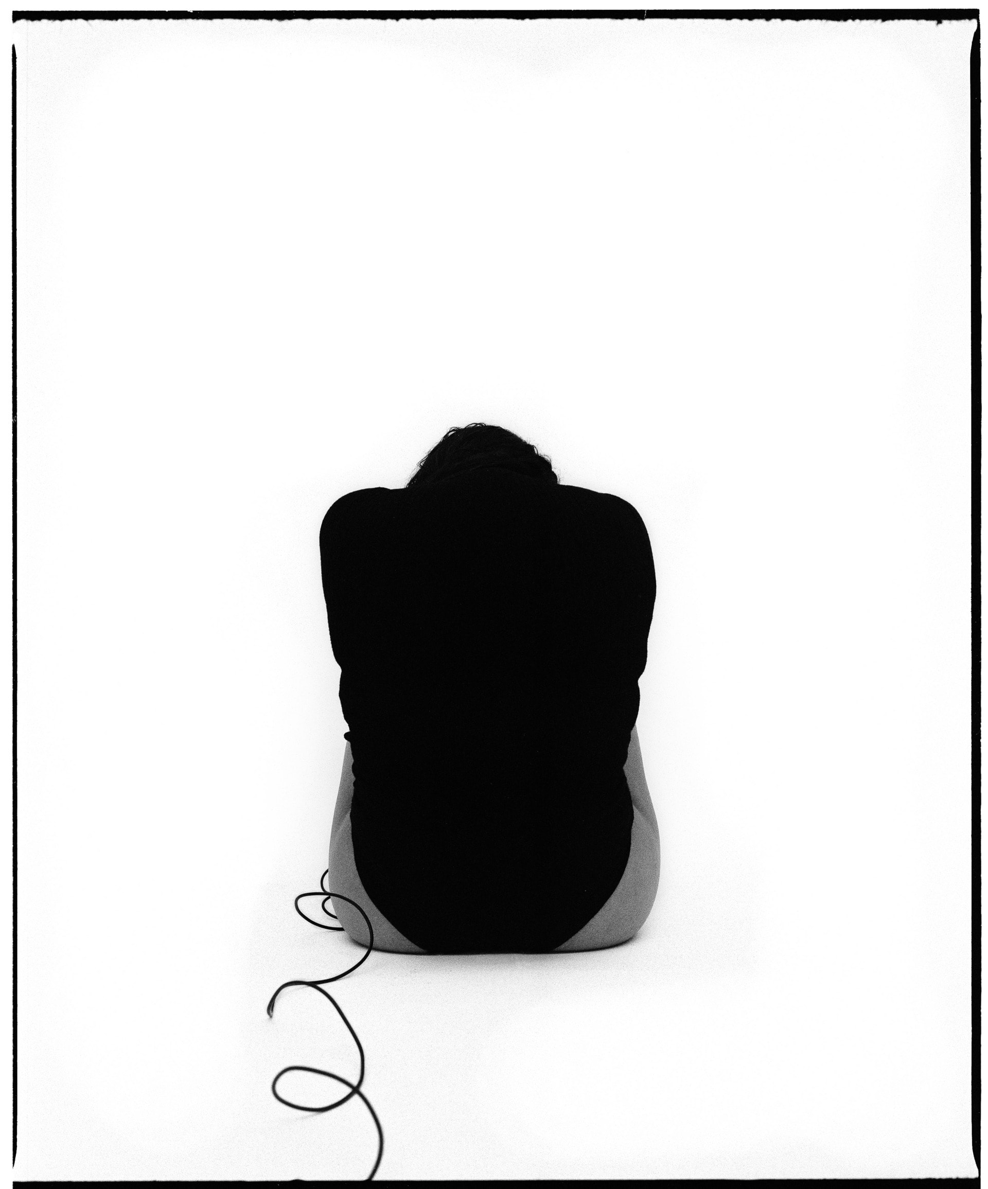 black and white self-portrait, curled up in a ball, back facing away from the camera